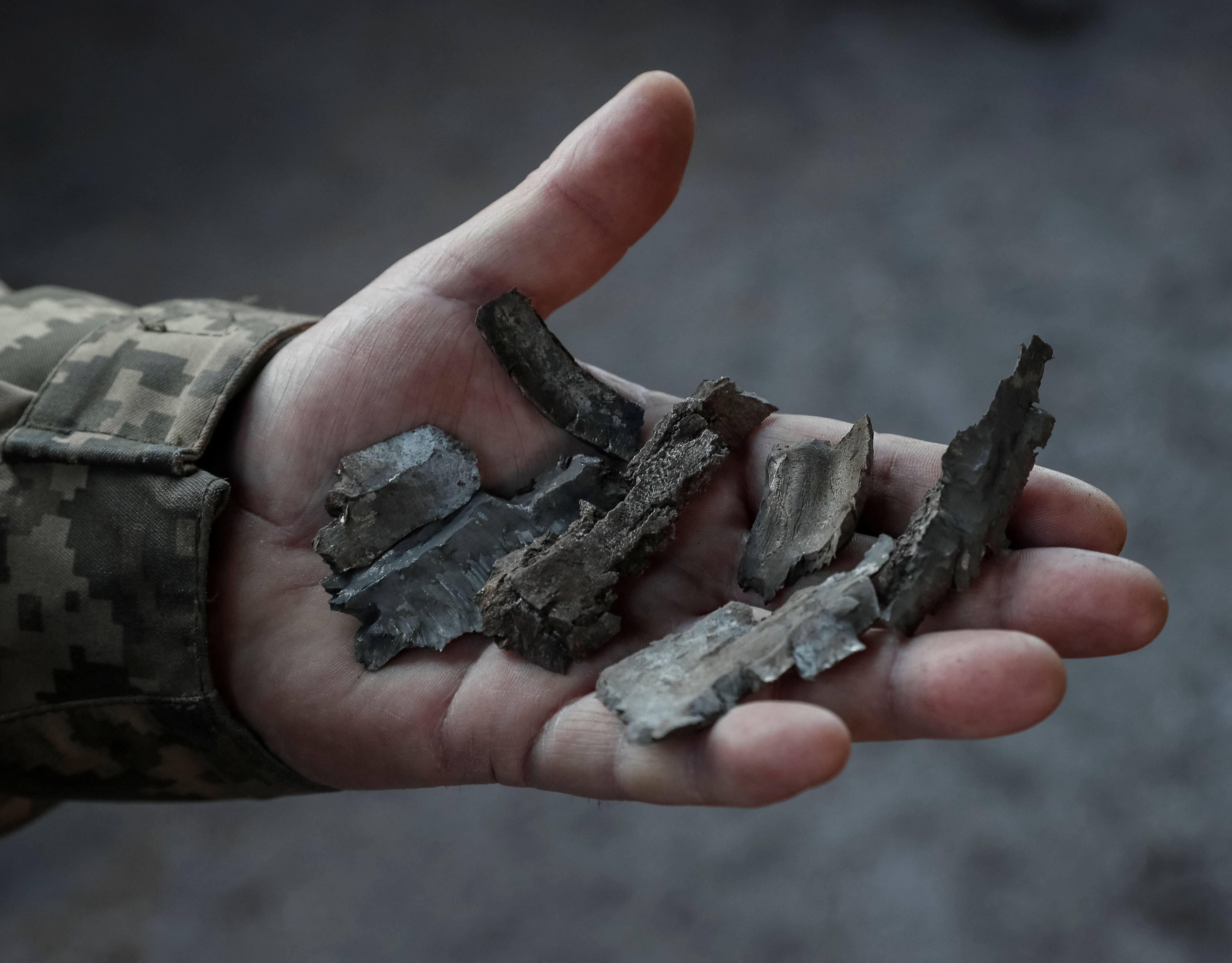 A Ukrainian service member shows shell fragments on the front line near the village of Zaitseve in the Donetsk region