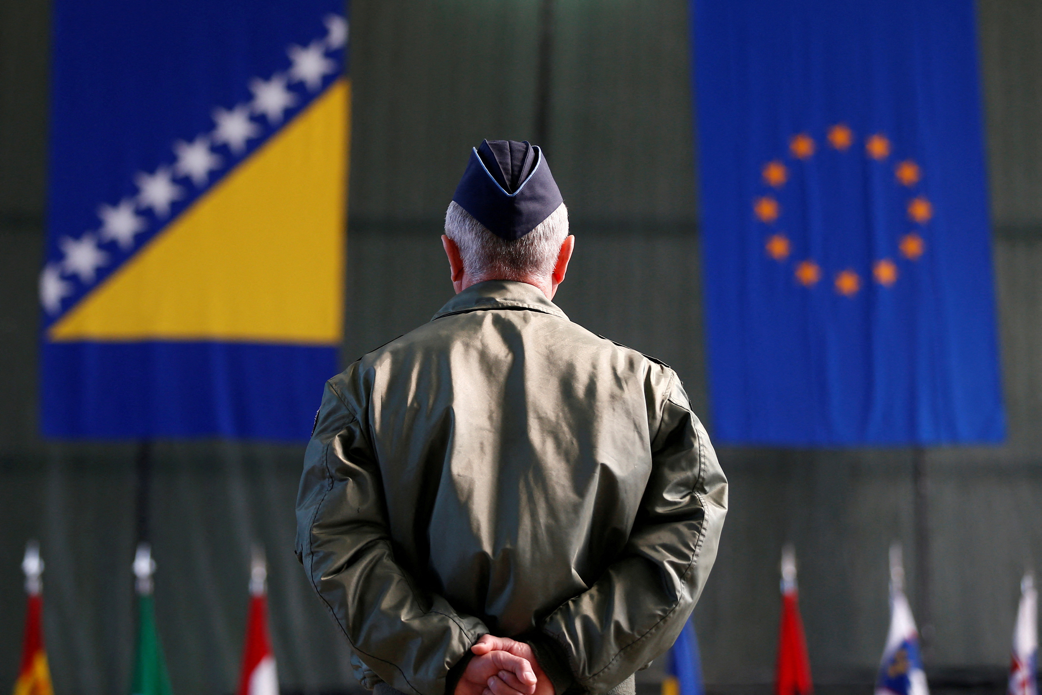 Member of European Forces (EUFOR) stands in front of the Bosnia and Herzegovina and EU flags during Change of Command Ceremony, in Sarajevo