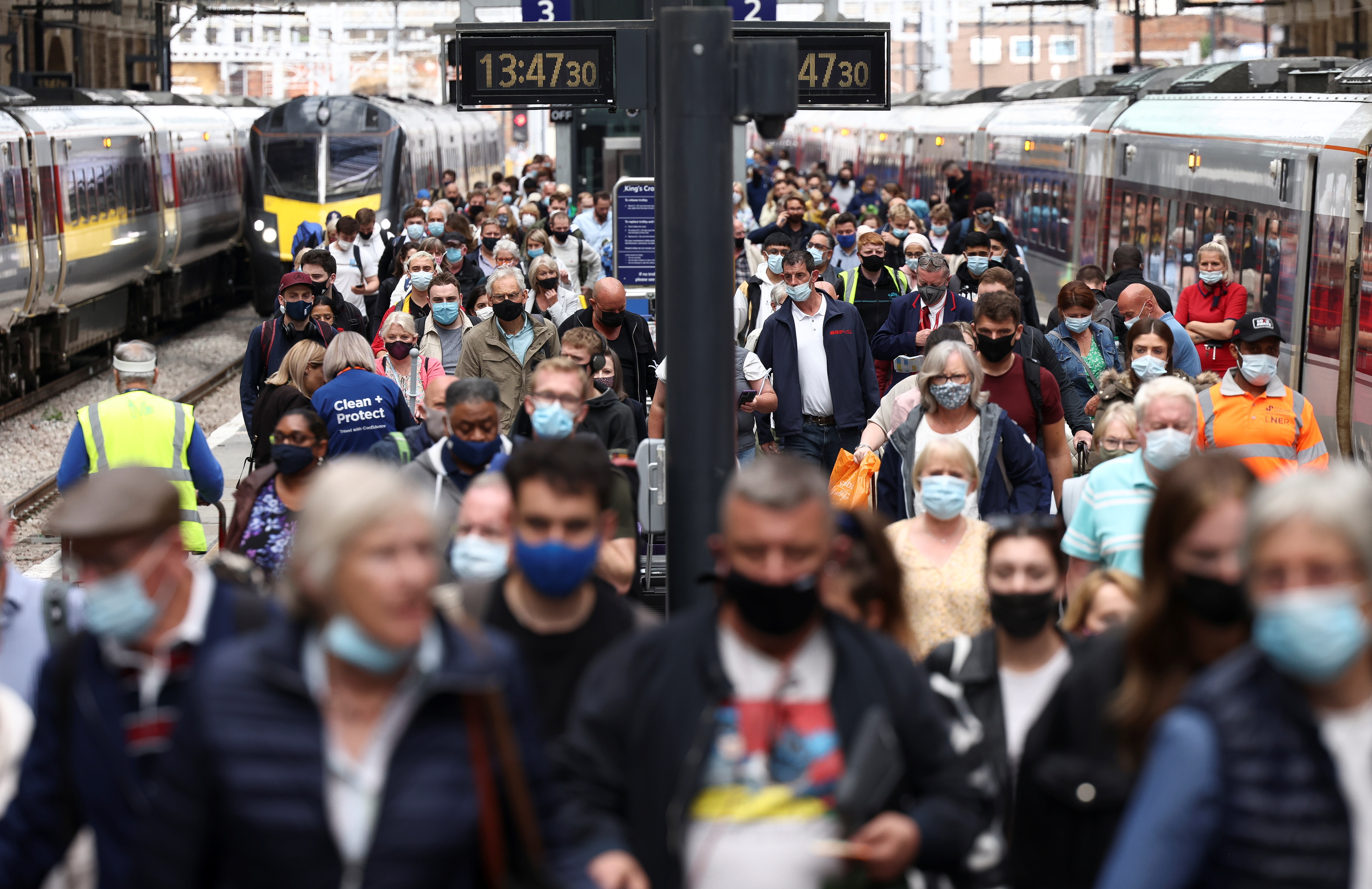 People wearing protective face masks walk along a platform at King's Cross Station, amid the coronavirus disease (COVID-19) outbreak in London