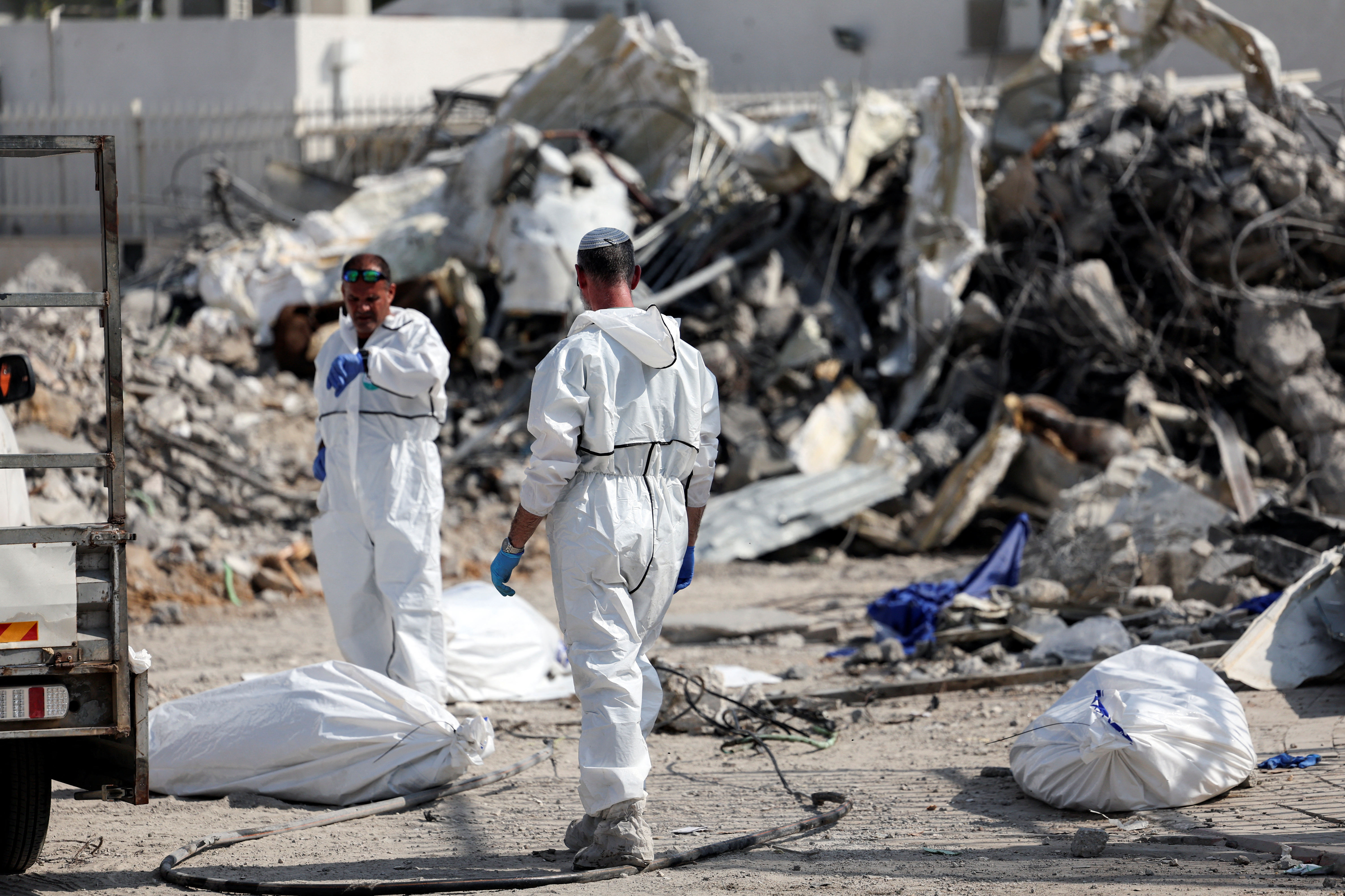 Israeli rescue workers work to remove dead bodies from near a destroyed police station that was the site of a battle following a mass-infiltration by Hamas gunmen from the Gaza Strip, In Sderot