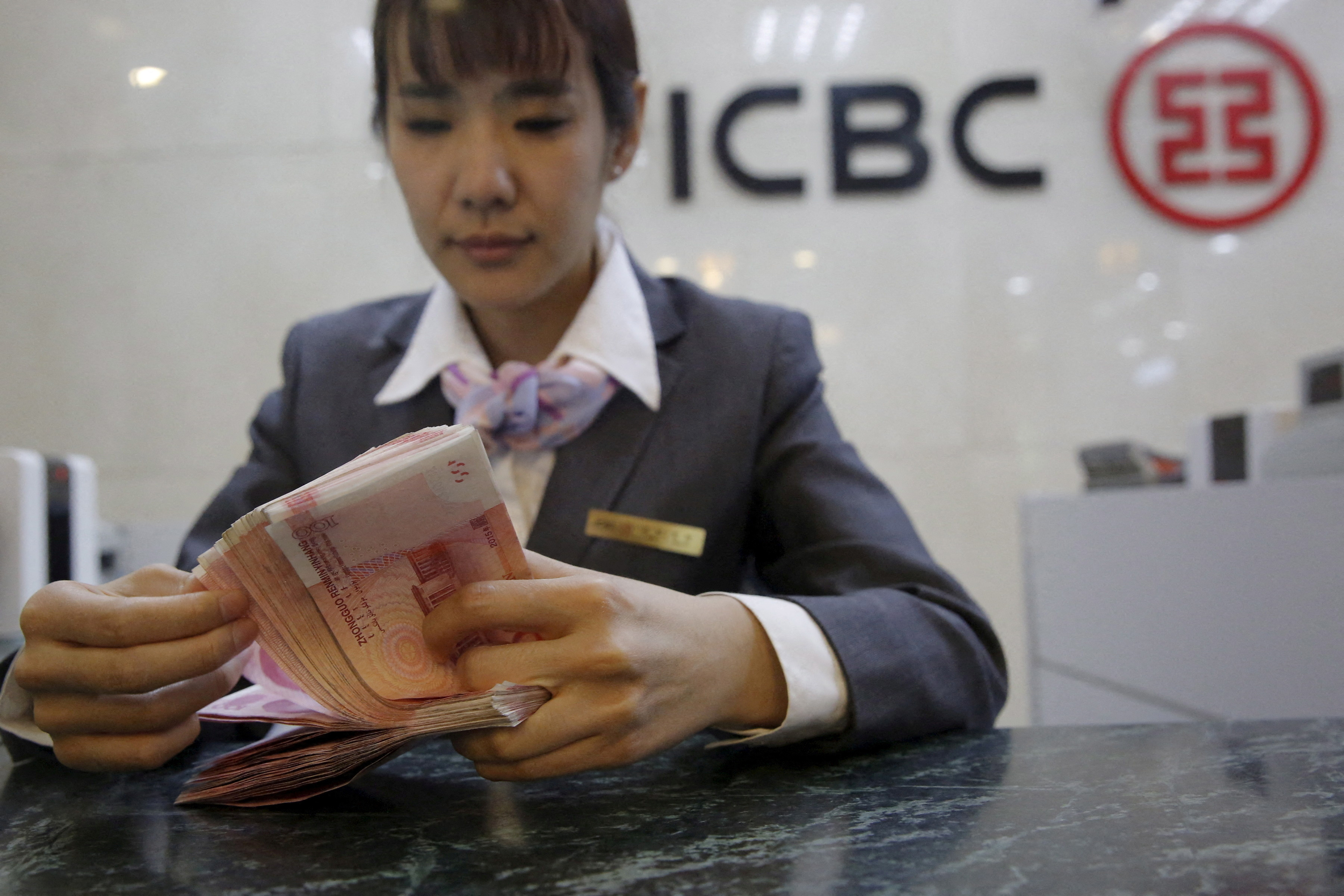 FILE PHOTO: A clerk of ICBC bank counts Chinese one hundred Yuan Banknotes as she poses for camera during a photo opportunity at its branch in Beijing