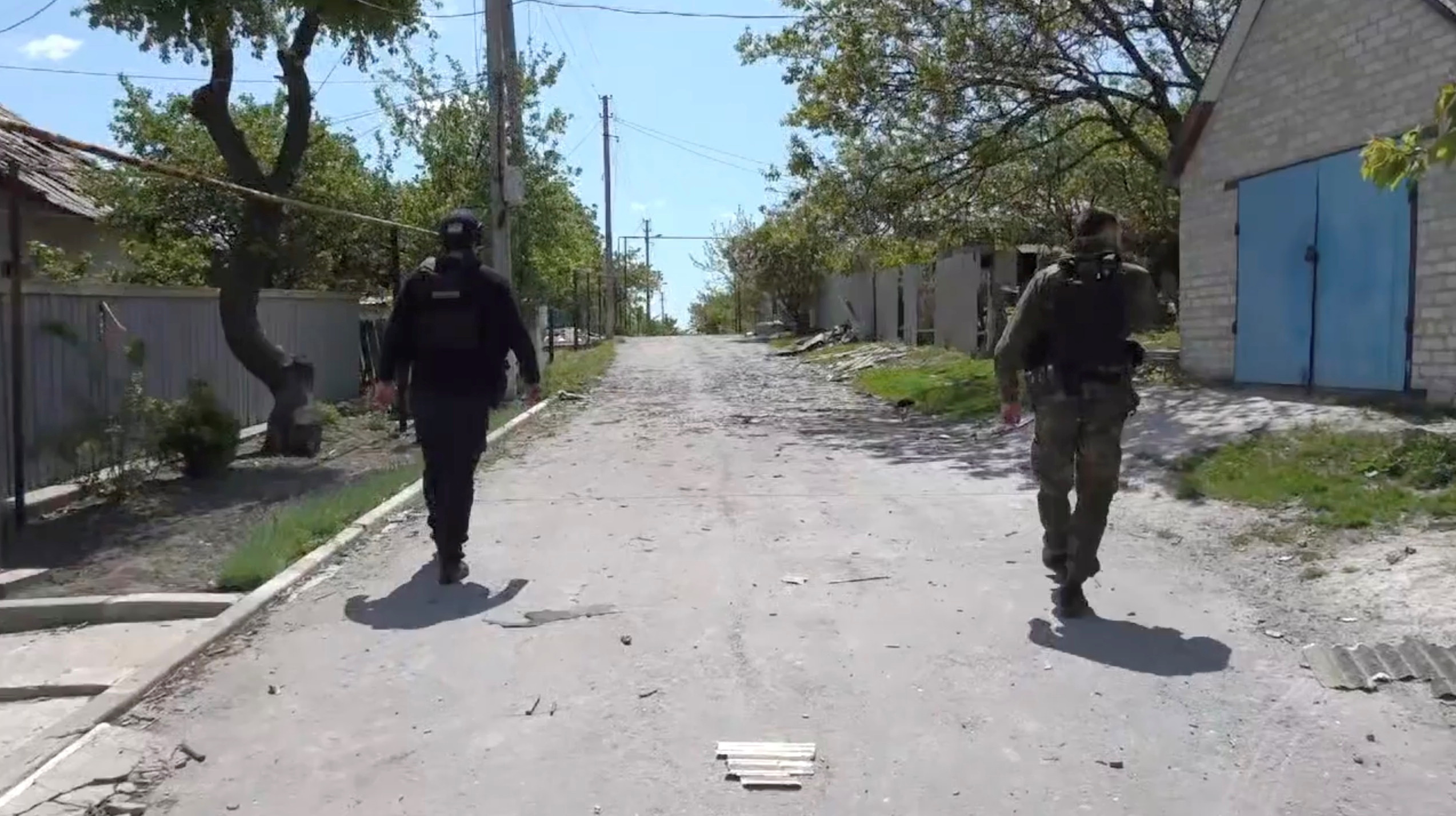 Members of the security forces walk on a street as they evacuate civilians, in Bilohorivka