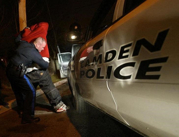 Camden police search a man in a Camden neighborhood.