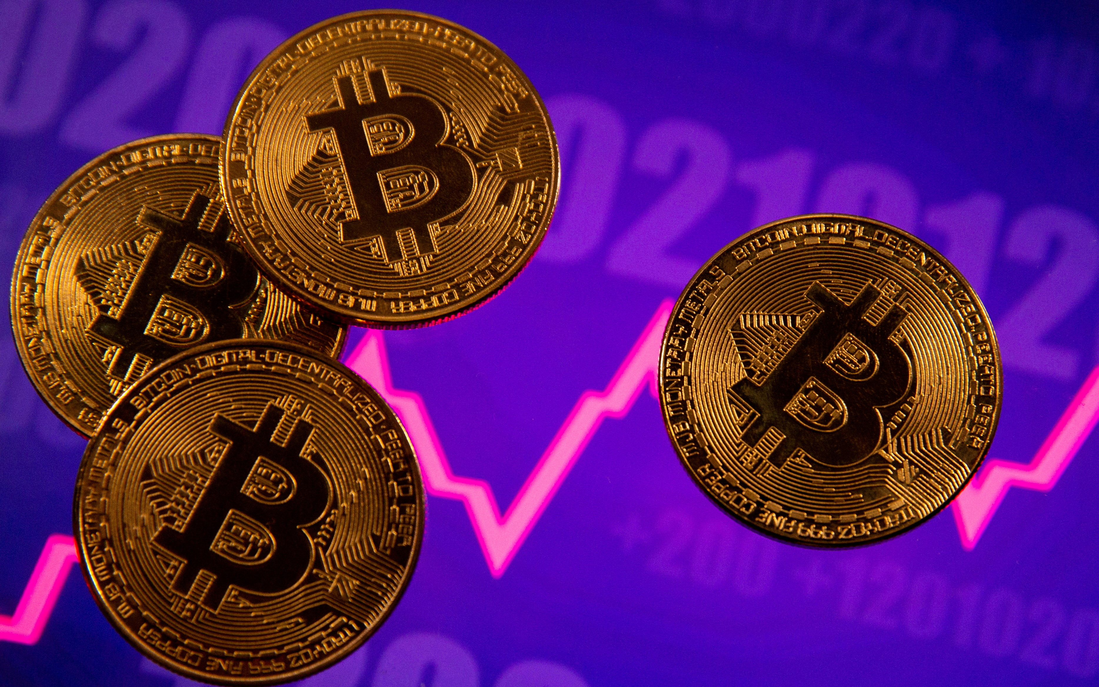 A representation of virtual currency Bitcoin is seen in front of a stock graph