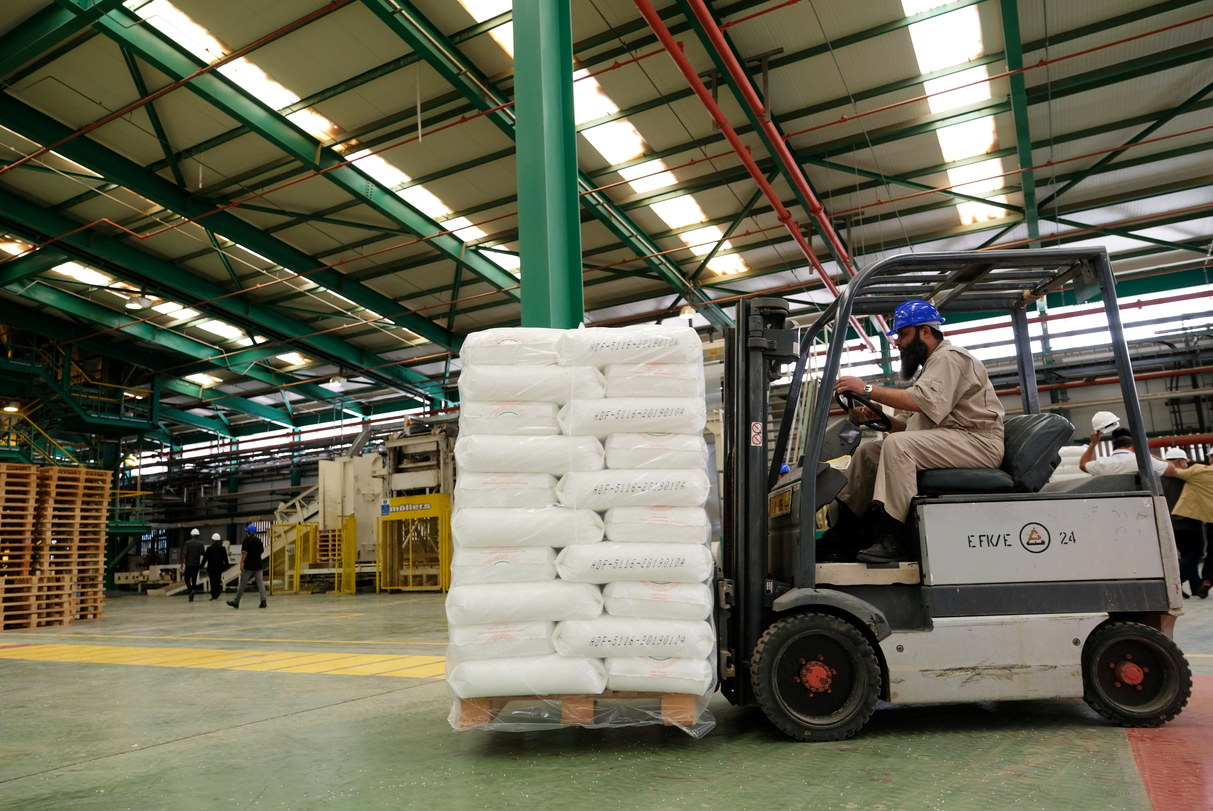 A worker carries polyethylene using a forklift during the reopening of a plastics factory in Ras Lanuf