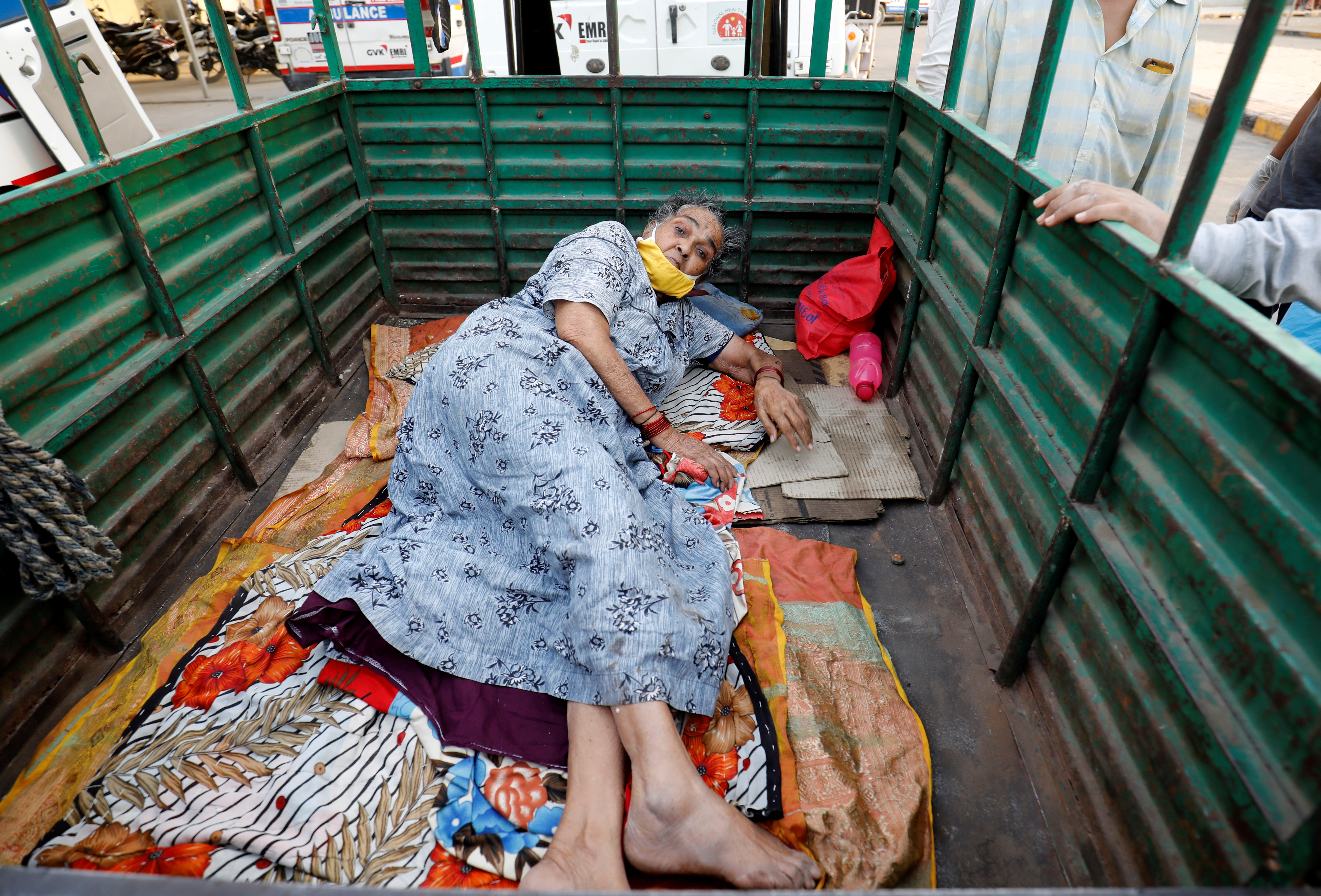 Woman lies in the back of a load carrier waiting to enter a COVID-19 hospital for treatment, in Ahmedabad