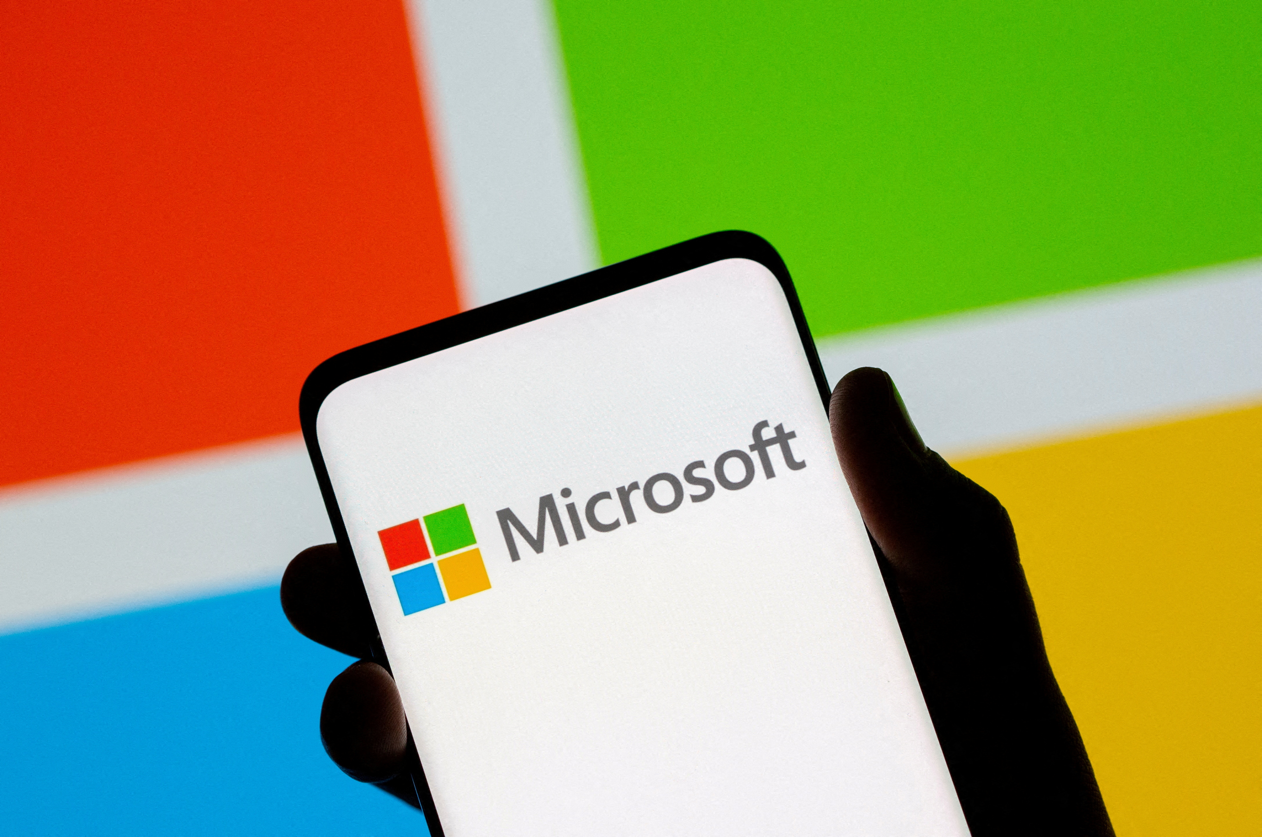 A smartphone is seen in front of the Microsoft logo in this illustration photo taken July 26, 2021. REUTERS/Dado Ruvic/Illustration/File Photo