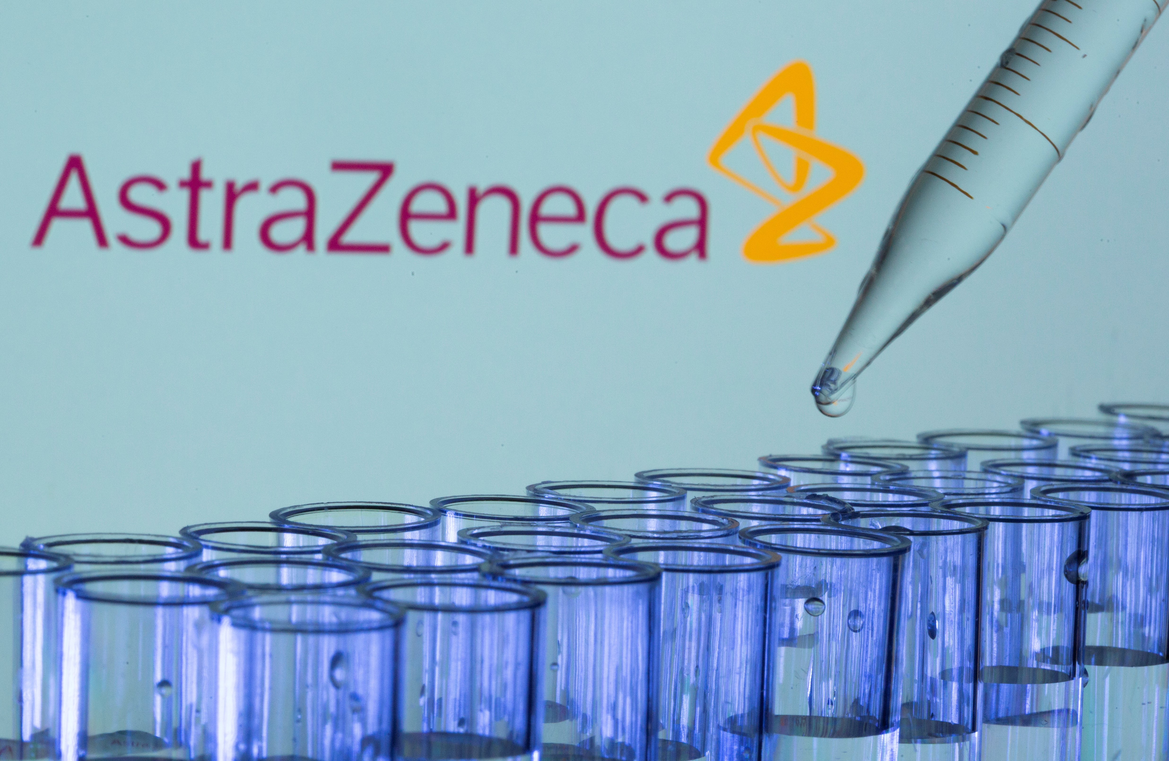 Test tubes are seen in front of a displayed AstraZeneca logo in this illustration