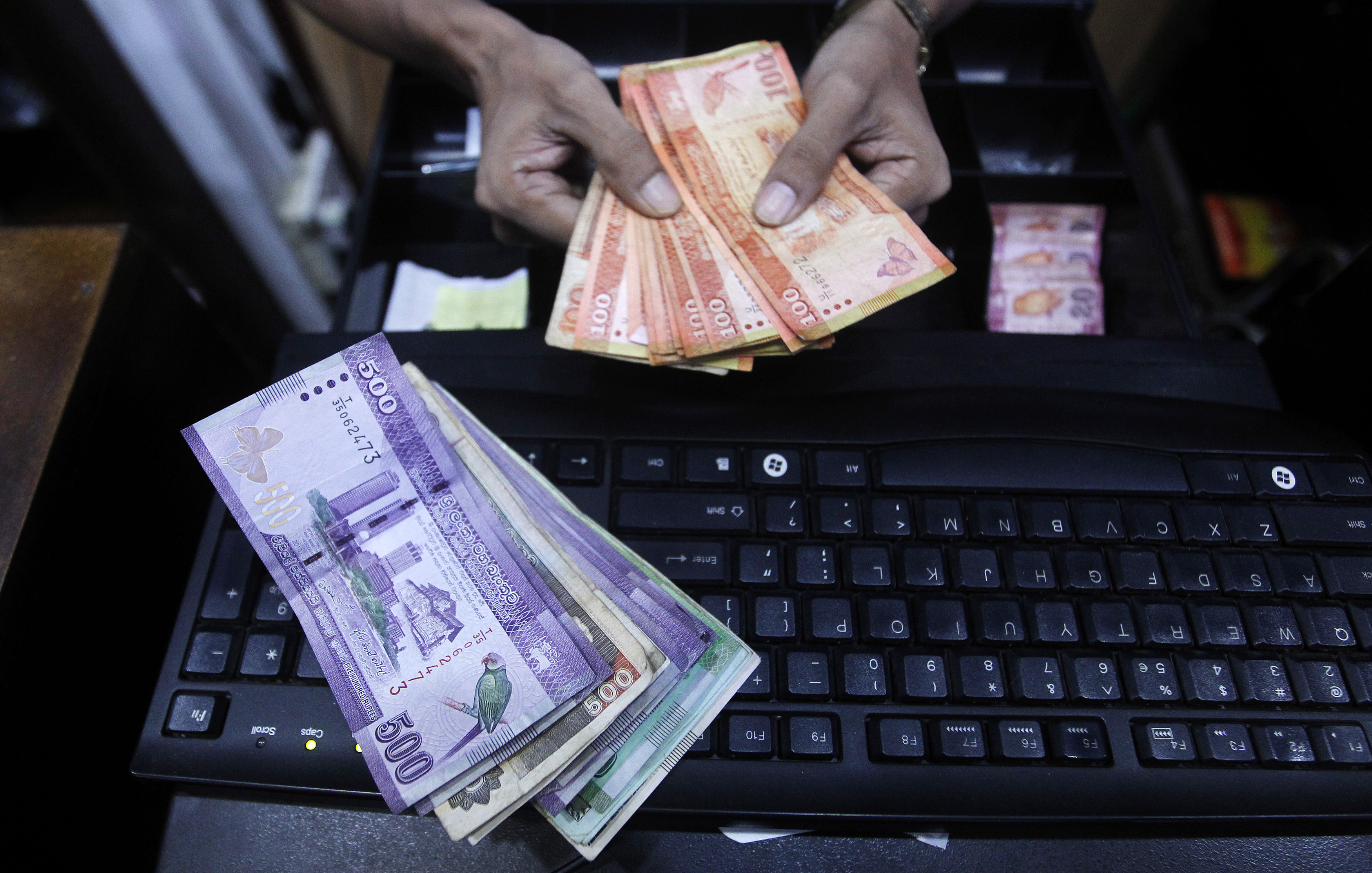 A vendor prepares Sri Lankan notes to bundle them at a shop in Colombo