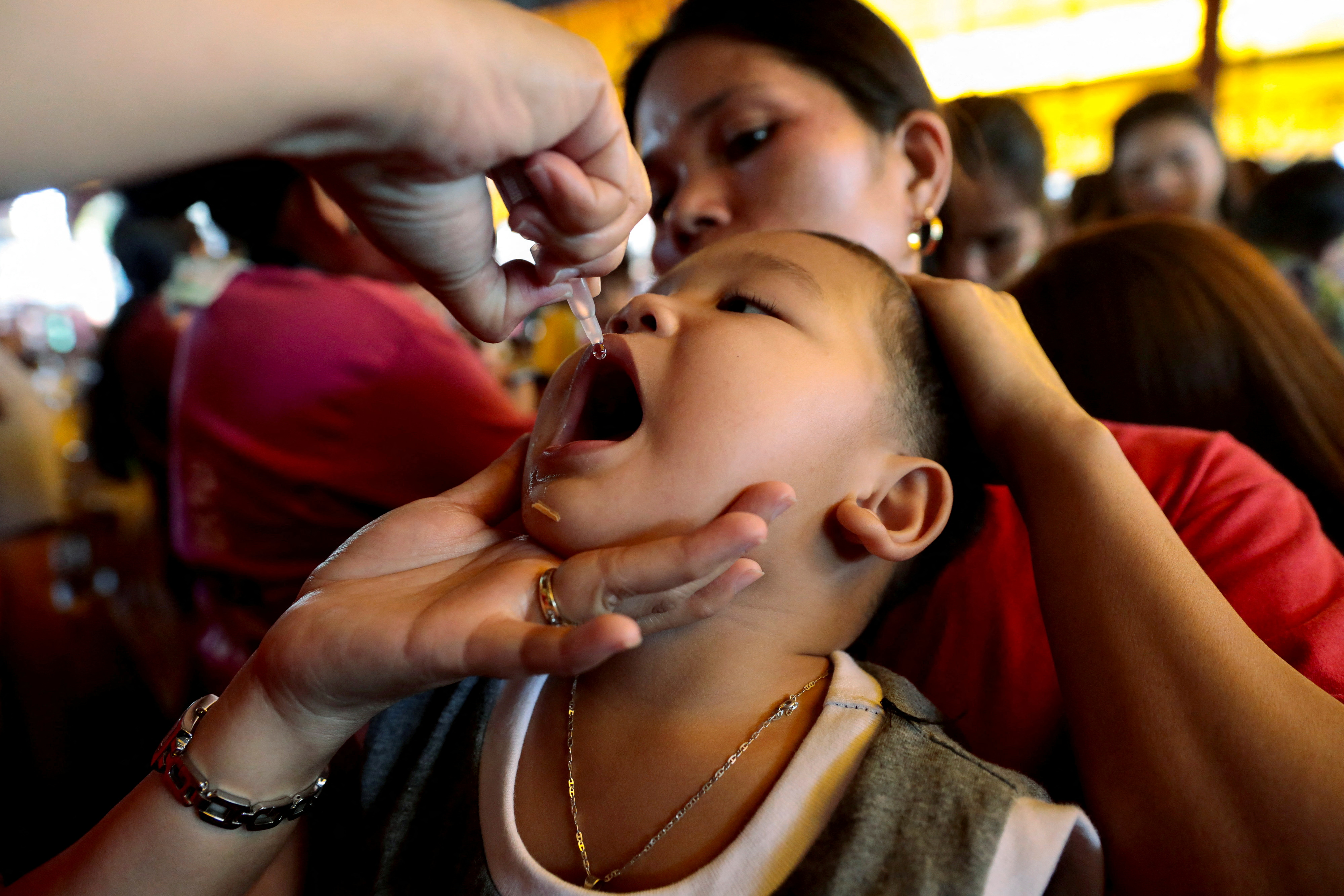 A child receives free polio vaccine during a government-led mass vaccination program in Quezon City