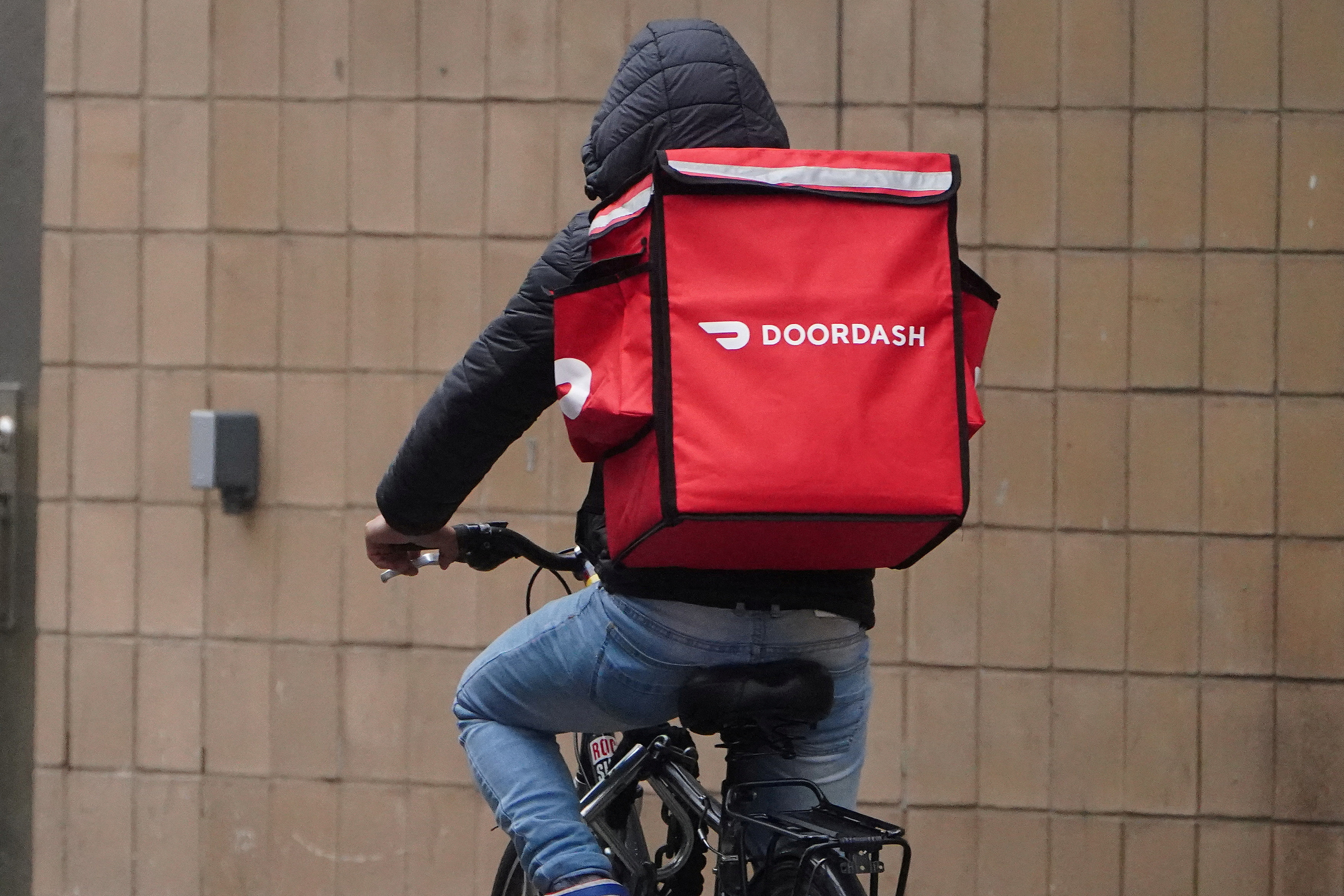 A delivery person for Doordash rides his bike in the rain during the coronavirus disease (COVID-19) pandemic in the Manhattan borough of New York City