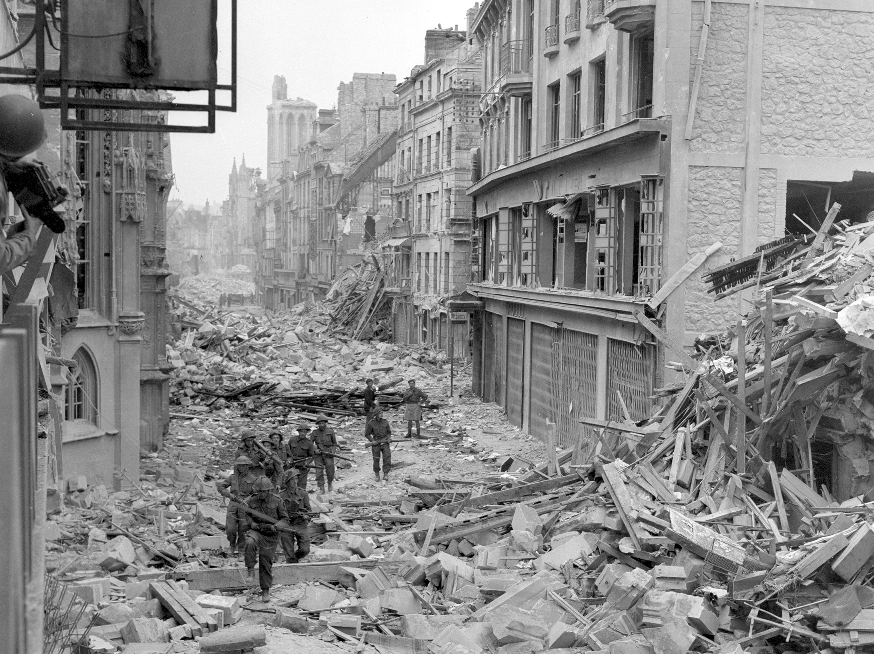 Handout photo of Canadian troops patrolling along the destroyed Rue Saint-Pierre after German forces were dislodged from Caen