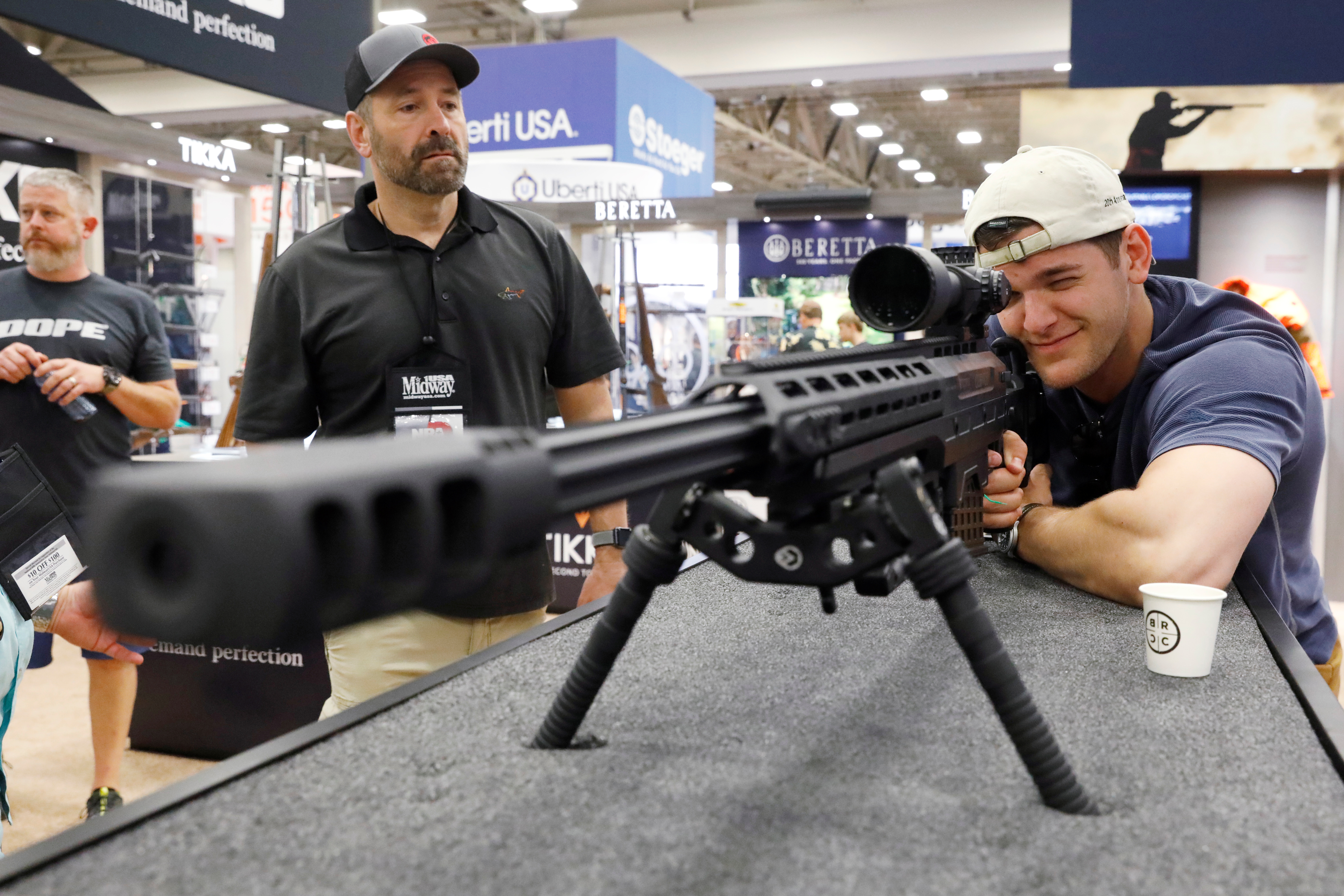 A man looks through a .50 caliber rifle during the annual National Rifle Association (NRA) convention in Dallas, Texas