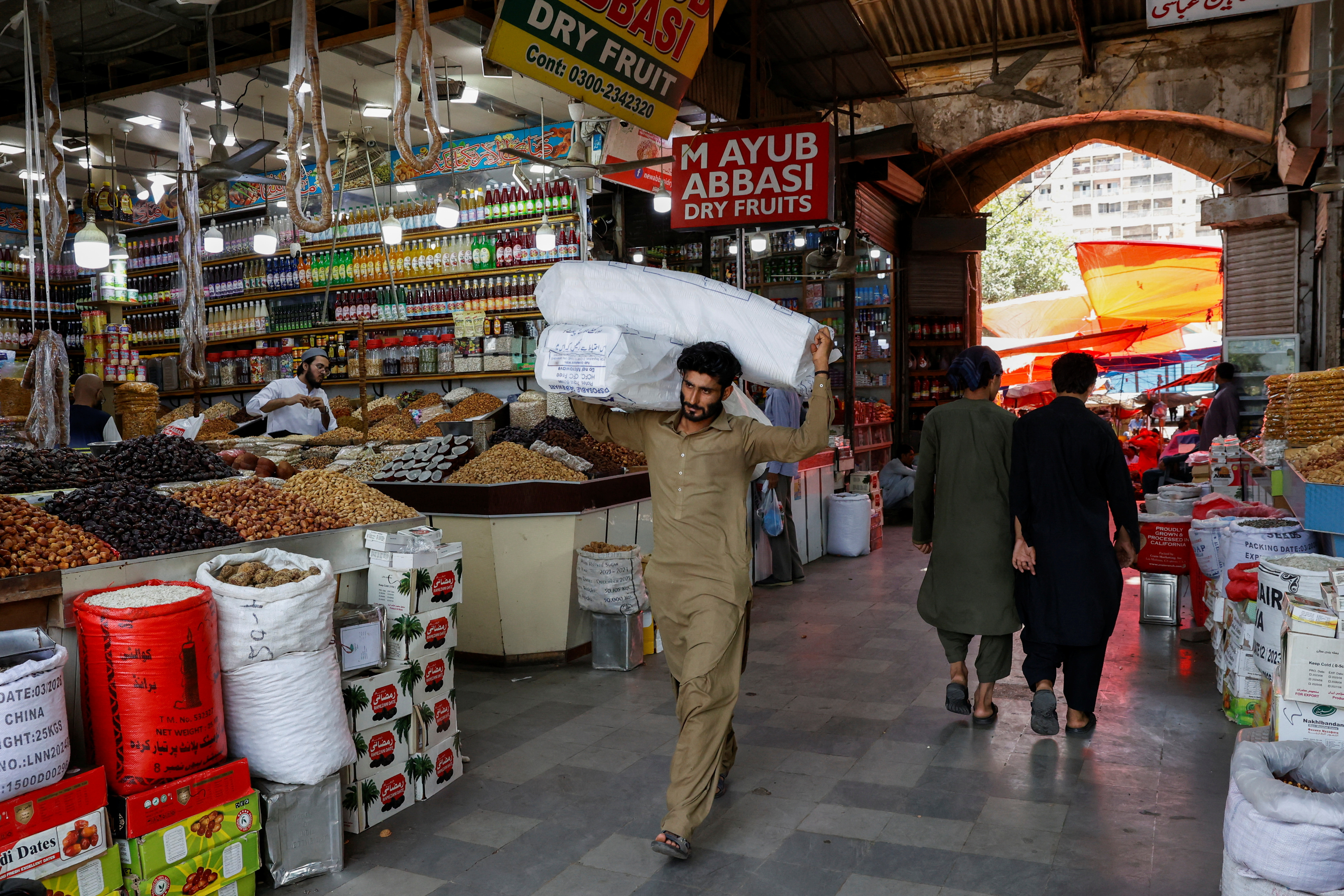 Man walks with sacks of supplies on his shoulder to deliver to a nearby shop at a market in Karachi