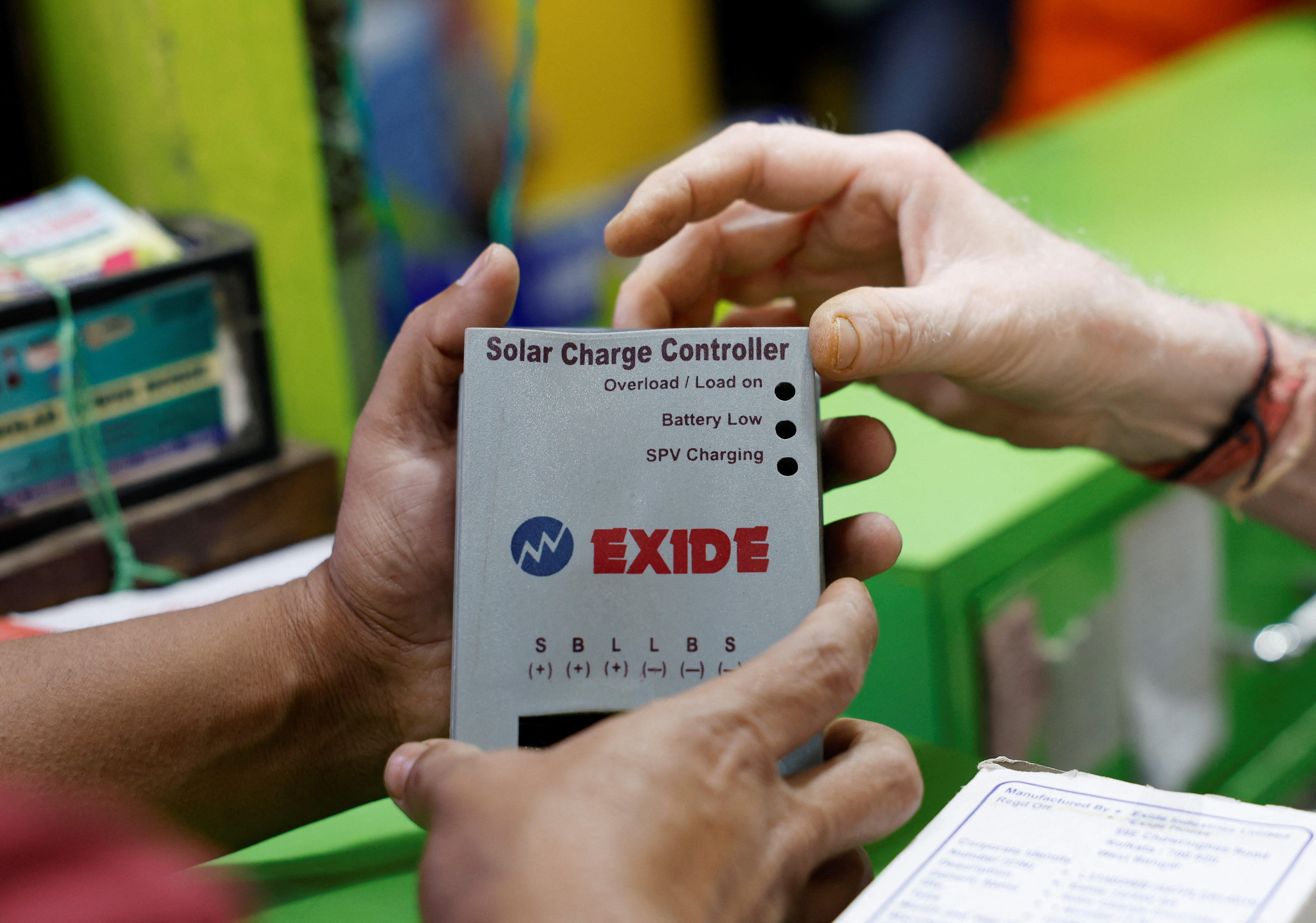 Customer looks at an Exide solar charge controller for purchase at a shop inside a wholesale electronics market in Kolkata