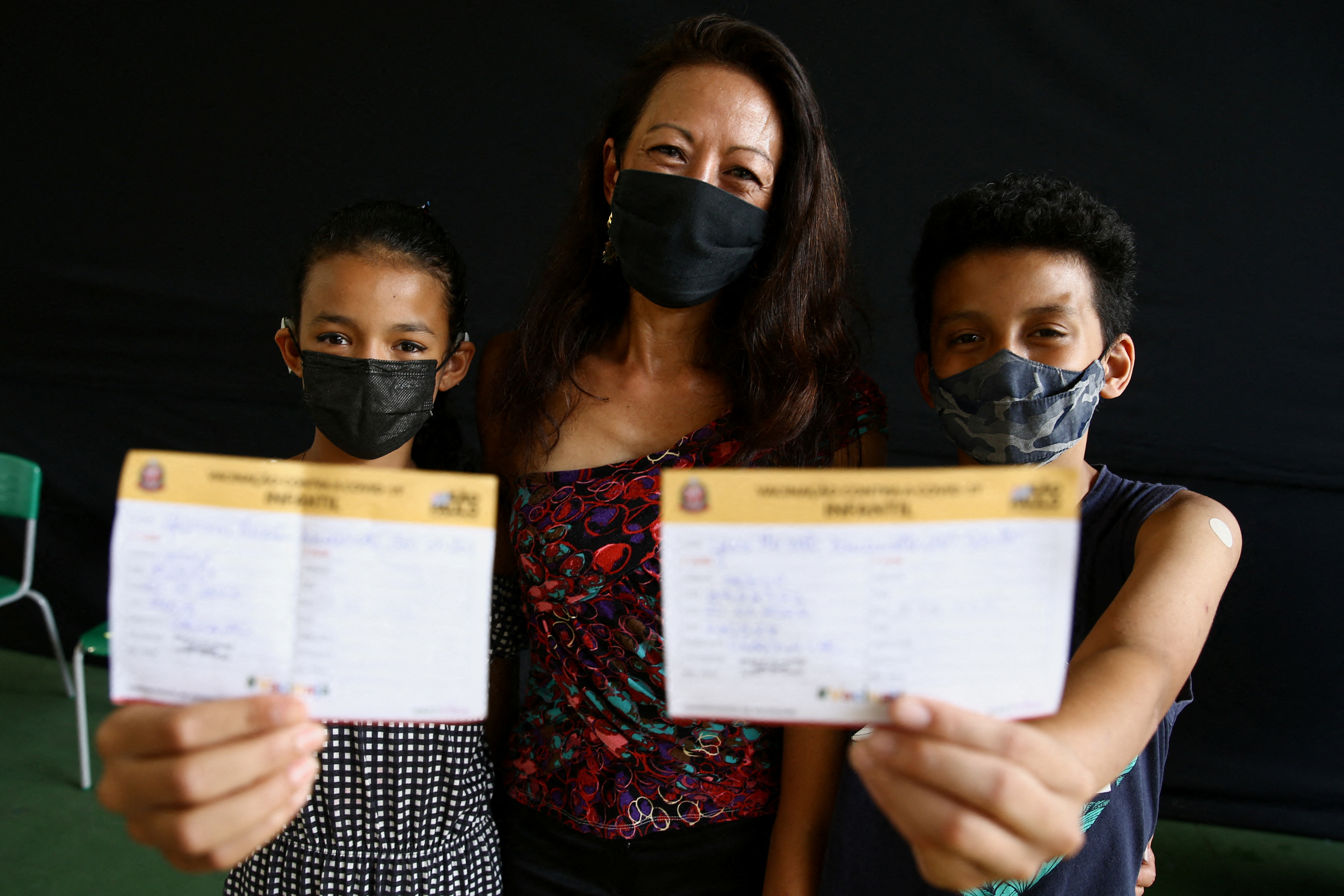 Angela Kawamoto dos Santos and her children Yasmin and Yuri pose for a photo after they received a dose of Sinovac Biotech's Coronavac vaccine against the coronavirus disease (COVID-19), as the National Health Surveillance Agency (ANVISA) approved its use for children, in Sao Paulo, Brazil, January 20, 2022. REUTERS/Carla Carniel