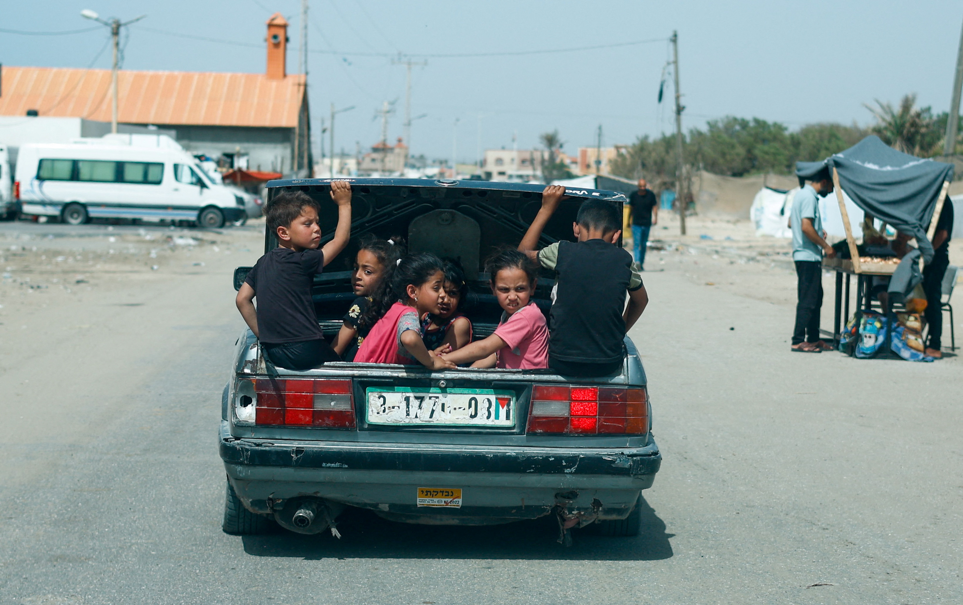 Children sit in a car trunk, in Rafah