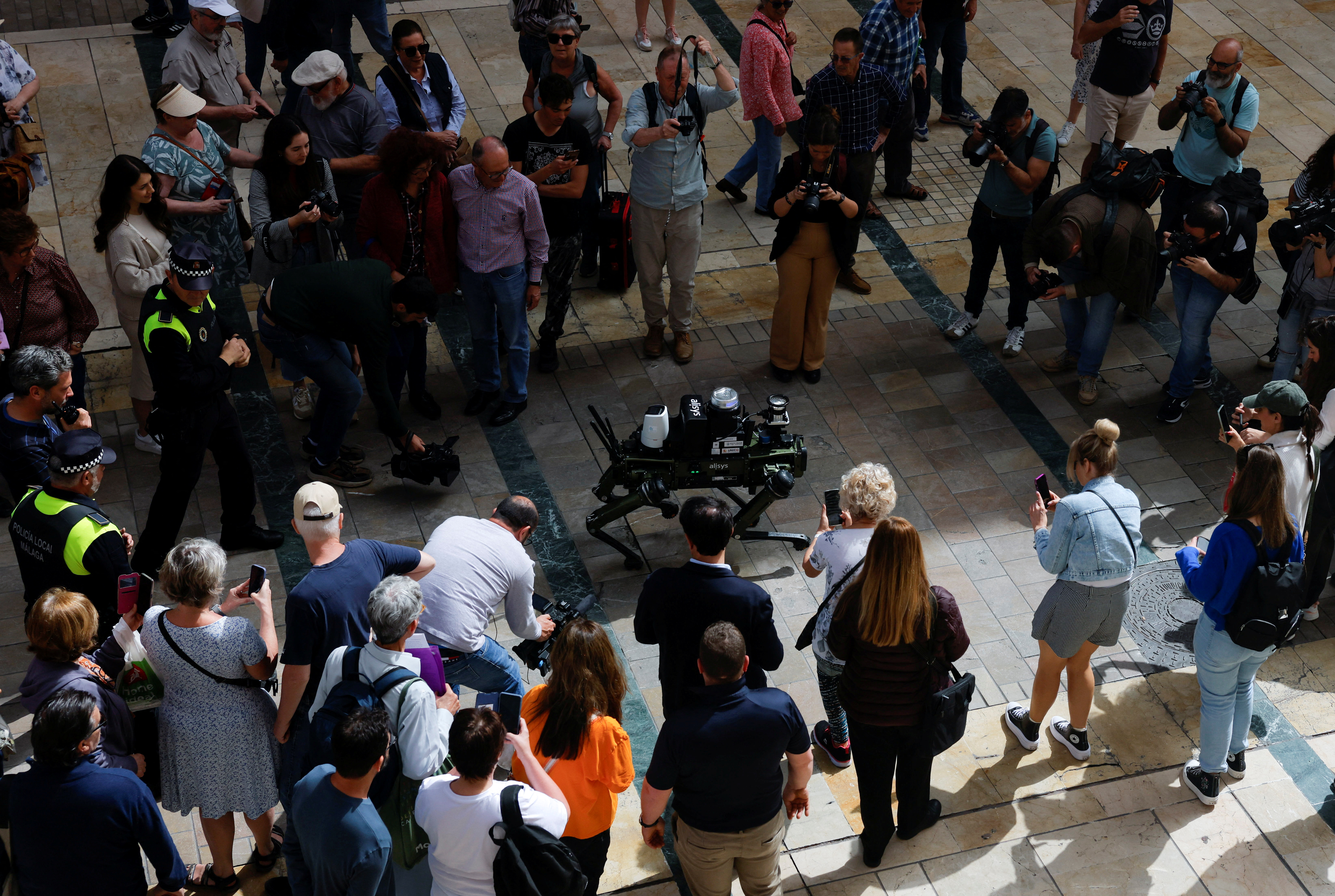  People watch a police robot dog aimed at helping enforce traffic laws for E-scooters, during its presentation to the media, in Malaga, southern Spain March 19, 2024. REUTERS/Jon Nazca 