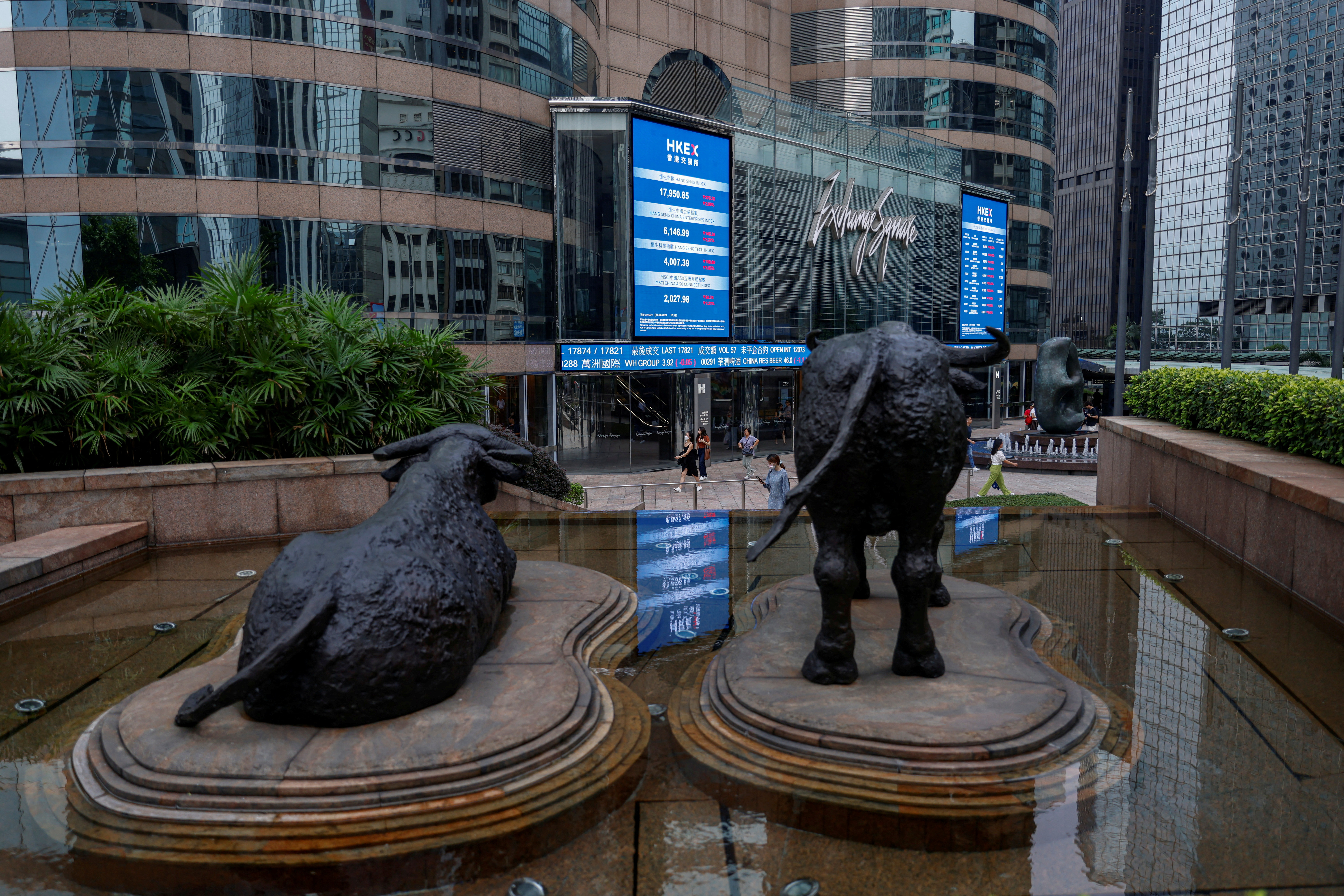 Bull statues in front of screens showing Hong Kong stock prices outside Exchange Square, in Hong Kong