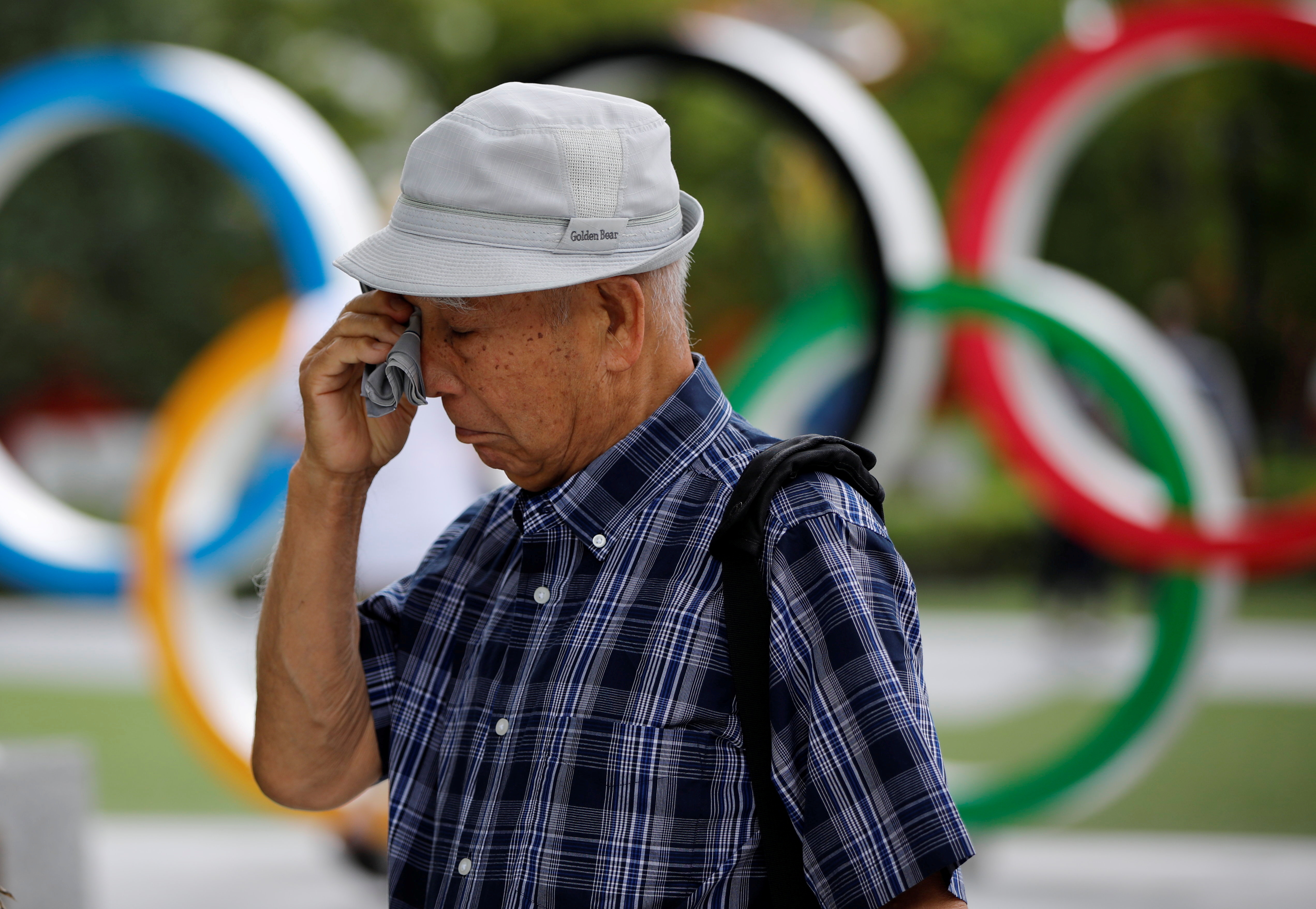 Kohei Jinno wipes his eyes in front of the Olympic Rings monument near the Natioonal Stadium in Tokyo