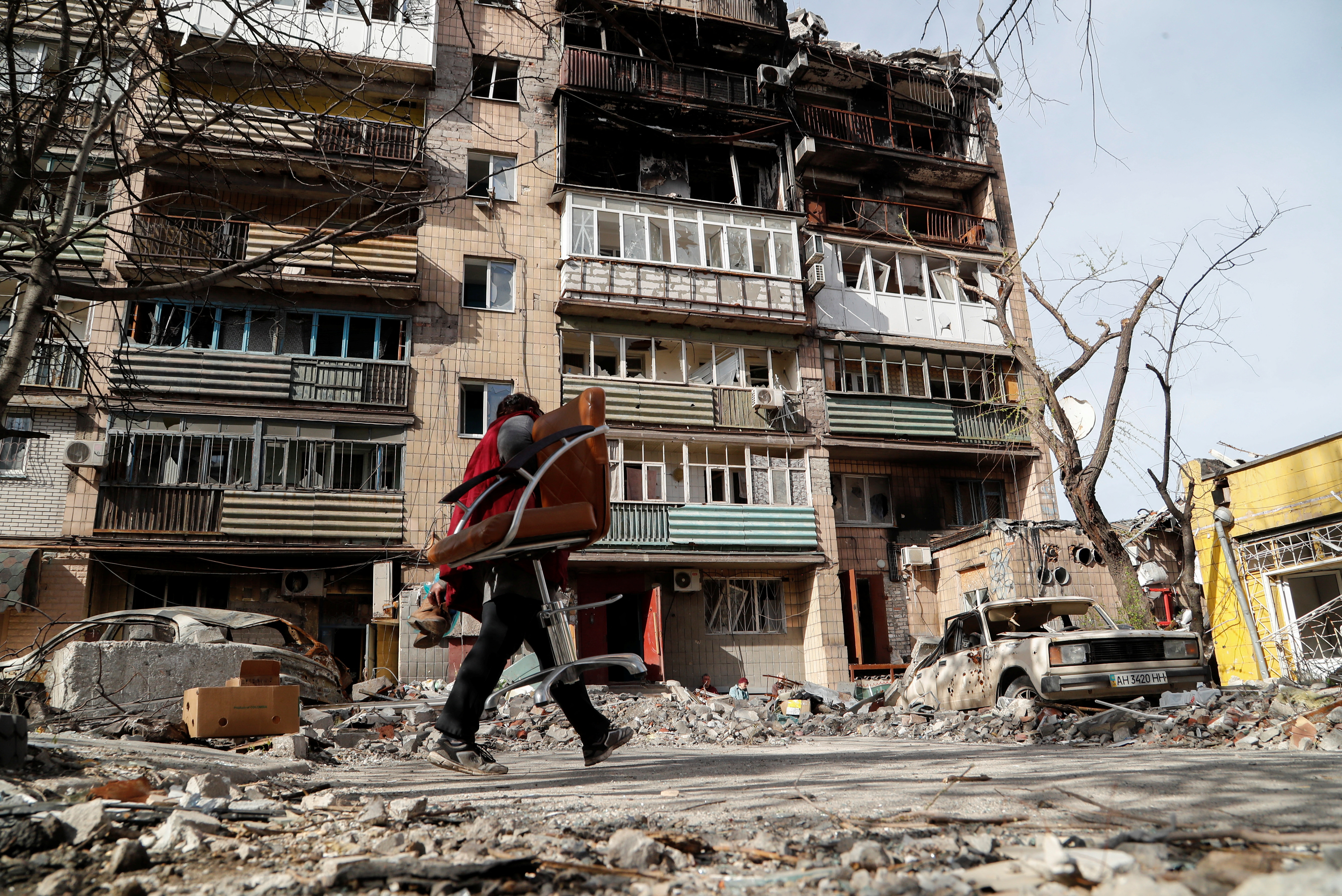 A local resident walks outside a damaged block of flats in Mariupol