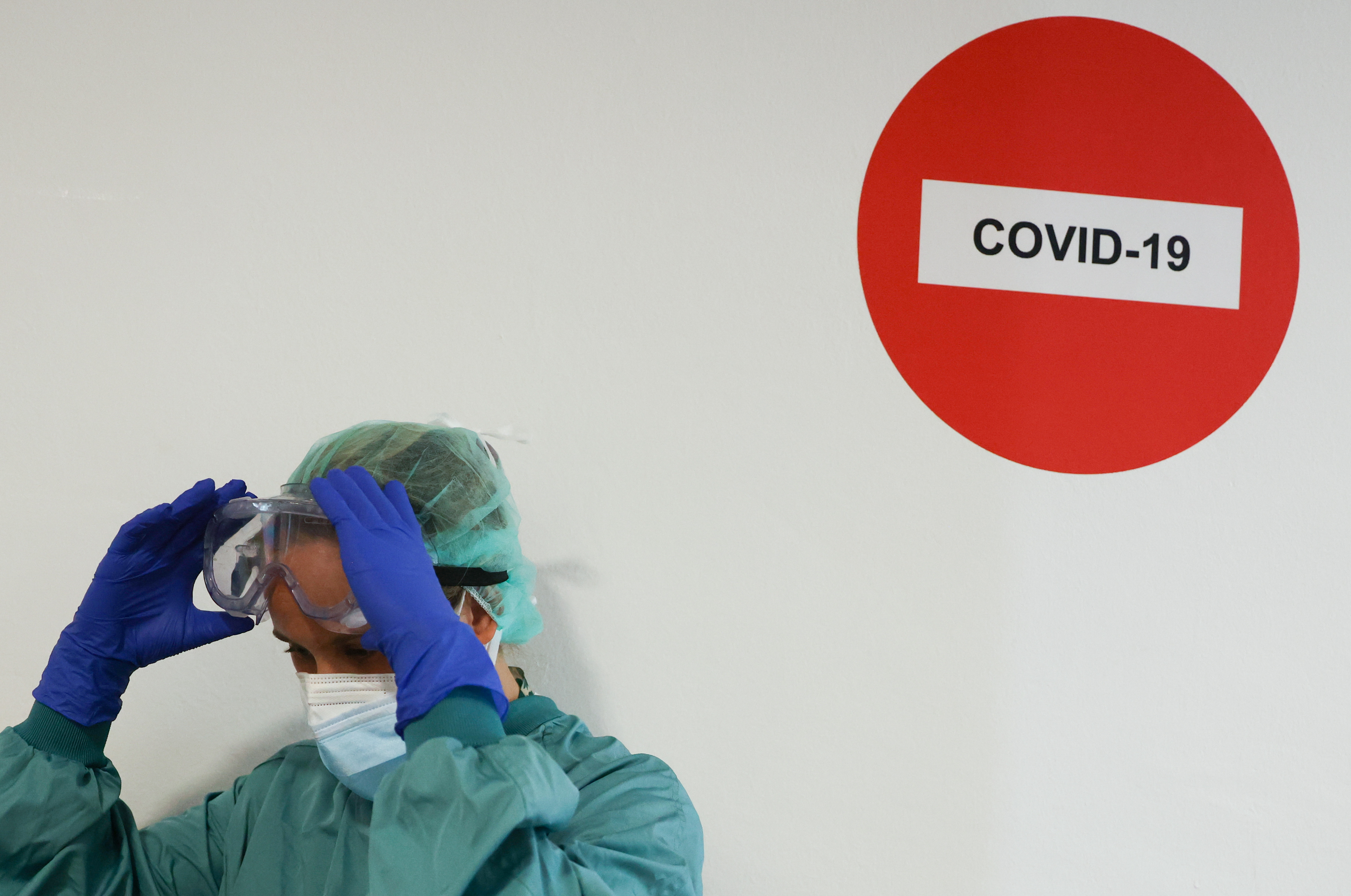 A hospital staff member adjusts protective glasses before treating a patient suffering from the coronavirus disease (COVID-19) at Hospital del Mar, where an additional ward has been opened to deal with an increase in coronavirus patients in Barcelona, Spain July 15, 2021.  REUTERS/Nacho Doce