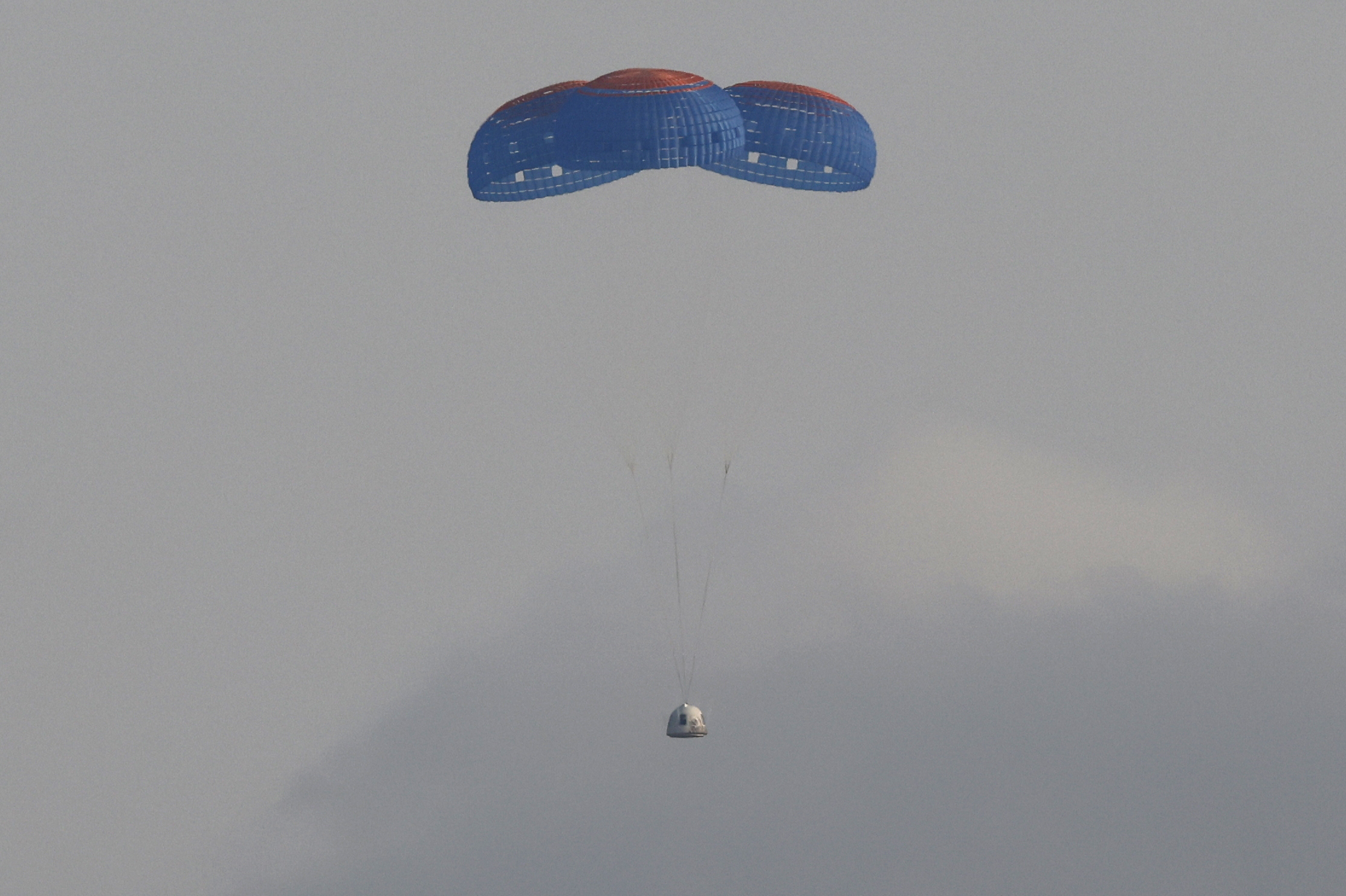 The capsule carrying billionaire businessman Jeff Bezos and three crew members returns by parachute after their flight aboard Blue Origin's New Shepard rocket near Van Horn, Texas , U.S., July 20, 2021. REUTERS/Joe Skipper