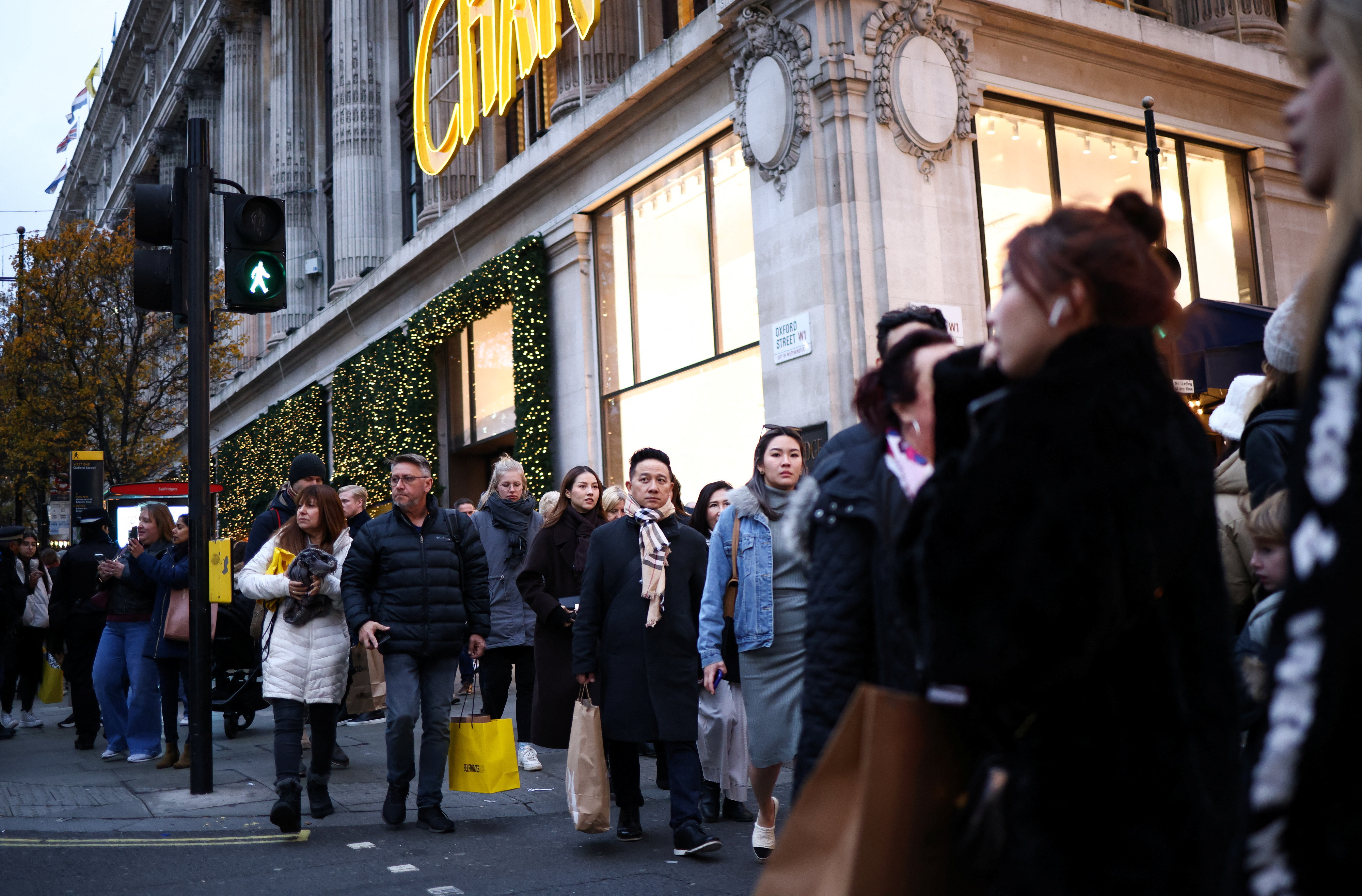 People carry shopping bags as they walk past Christmas themed shop displays on Oxford Street in London