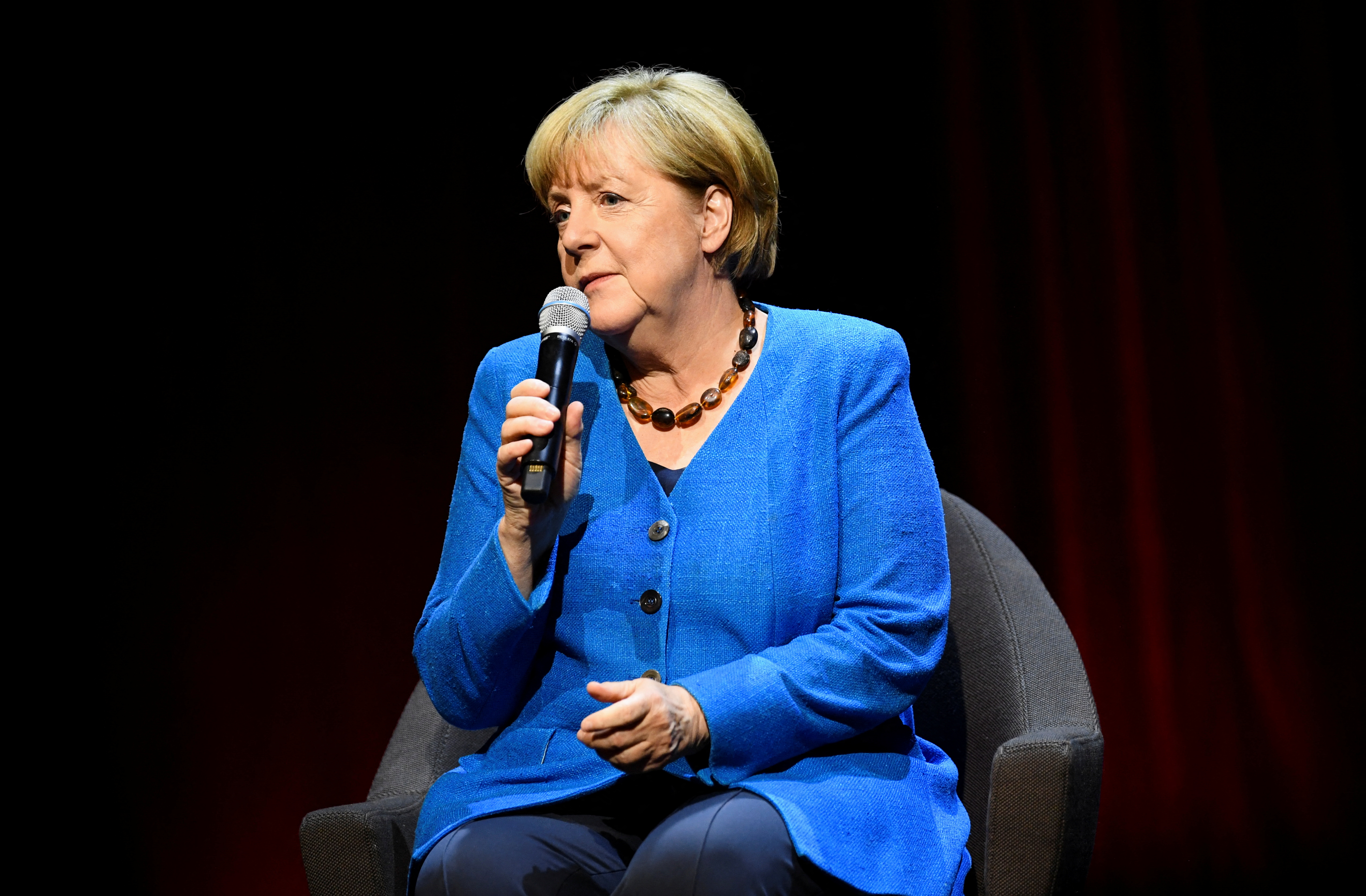 Former German Chancellor Angela Merkel talks with author Alexander Osang, in Berlin