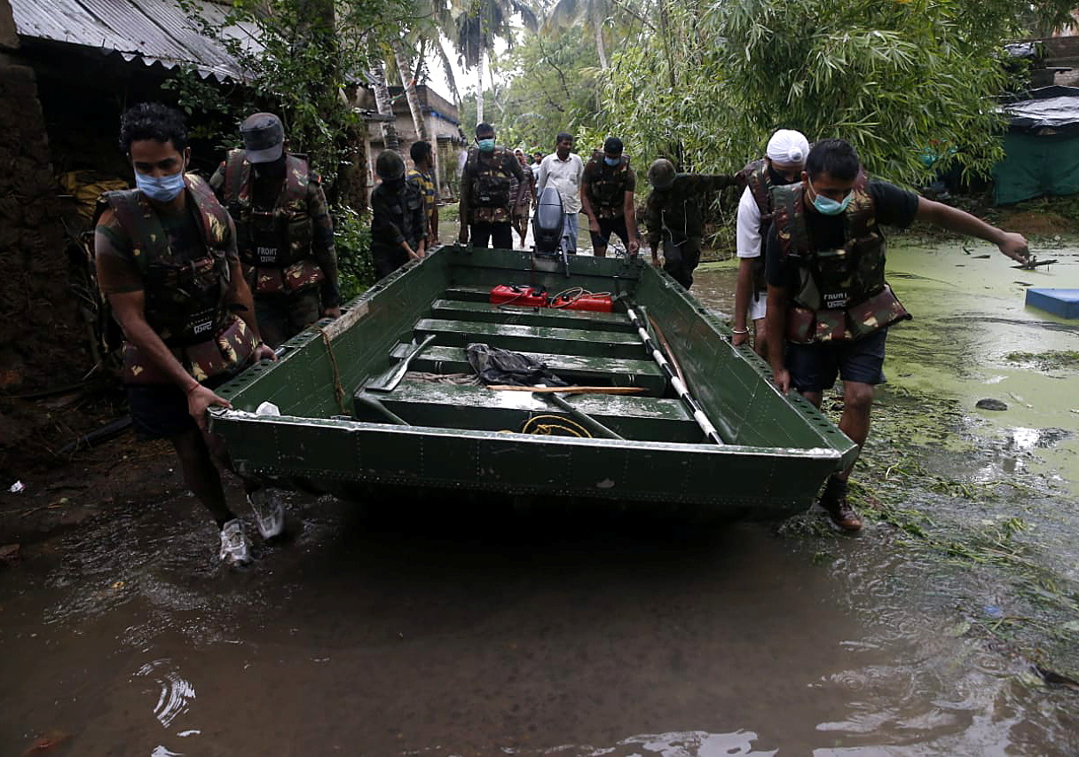 Army soldiers carry a boat to evacuate people from a flooded area as Cyclone Yaas makes landfall at Ramnagar