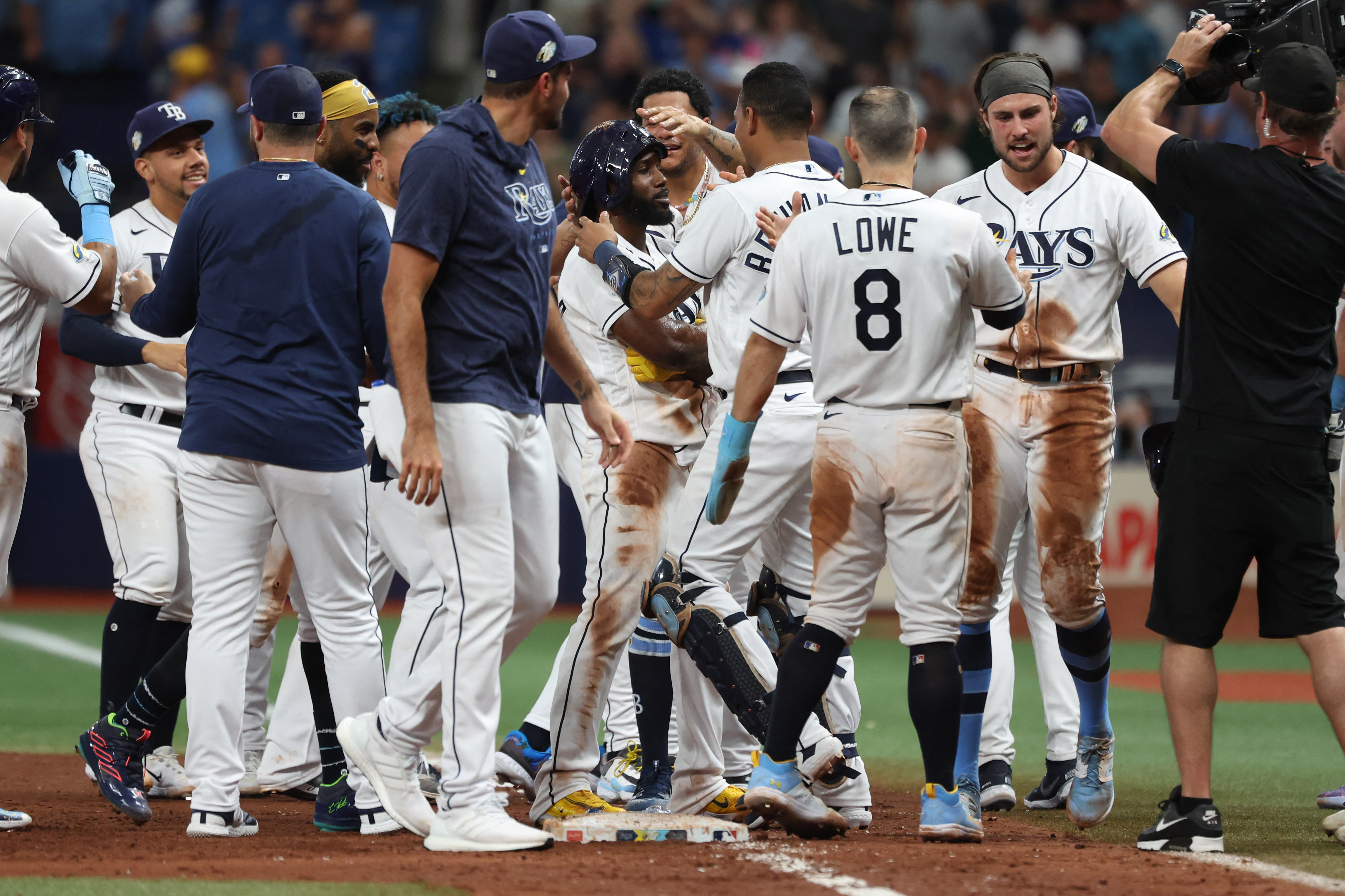 Tampa Bay Rays' Randy Arozarena is congratulated by teammates after scoring  the in the ninth inning of a baseball game against the Cleveland Indians,  Friday, July 23, 2021, in Cleveland. (AP Photo/Tony