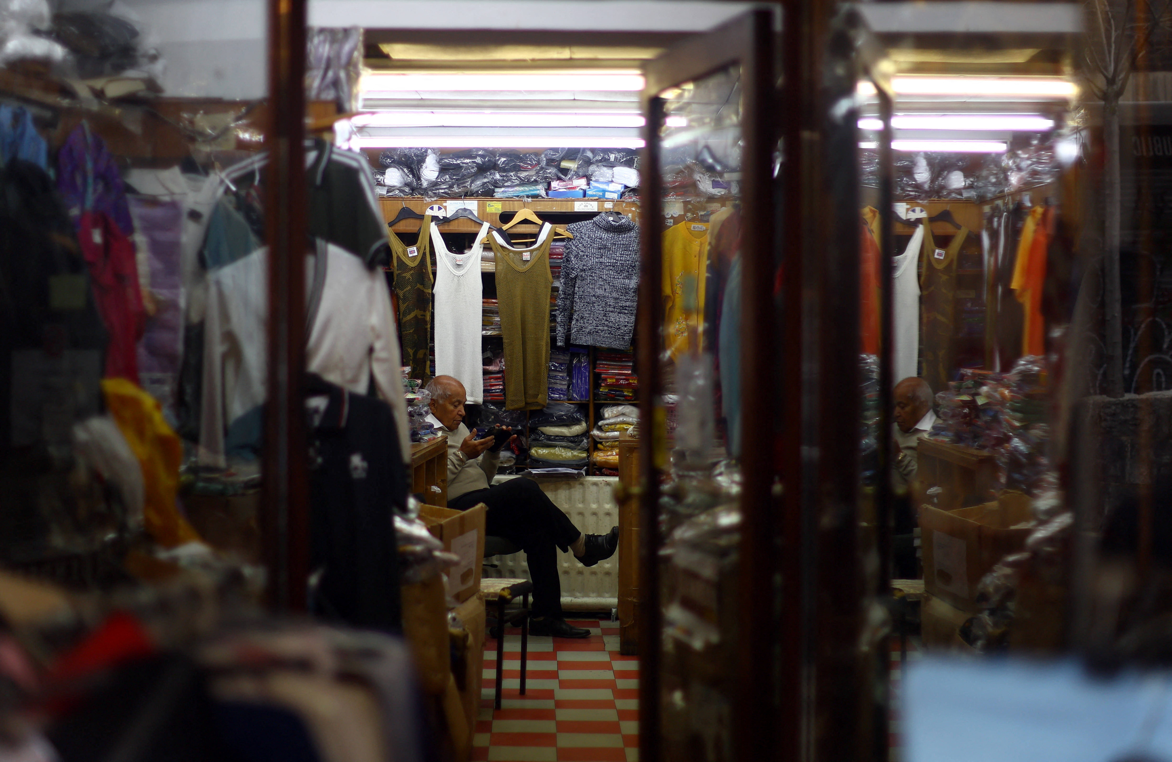 A shopkeeper waits for a customer inside a clothes store in London