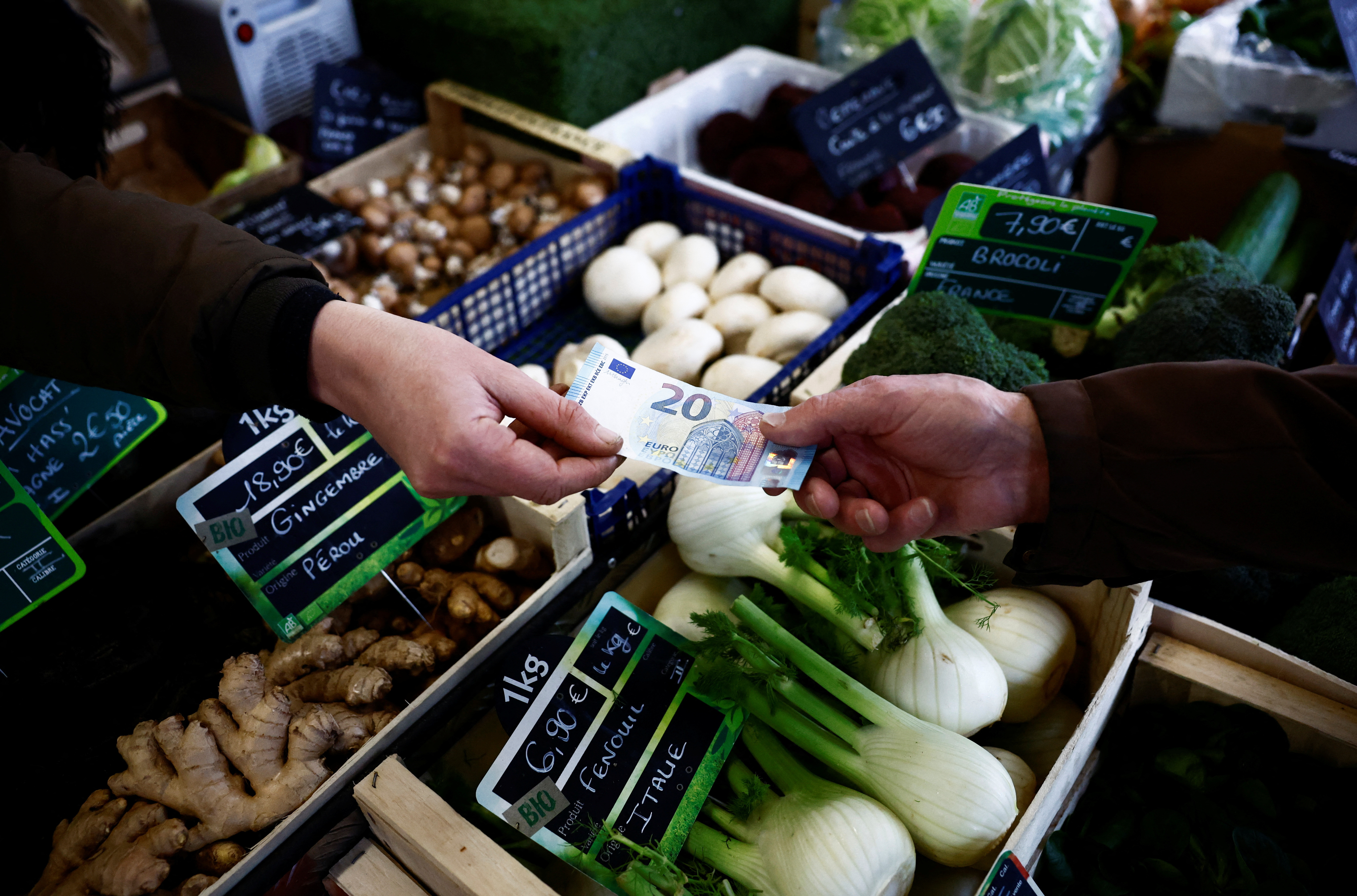 A shopper pays with a twenty Euro bank note at a local market in Nantes