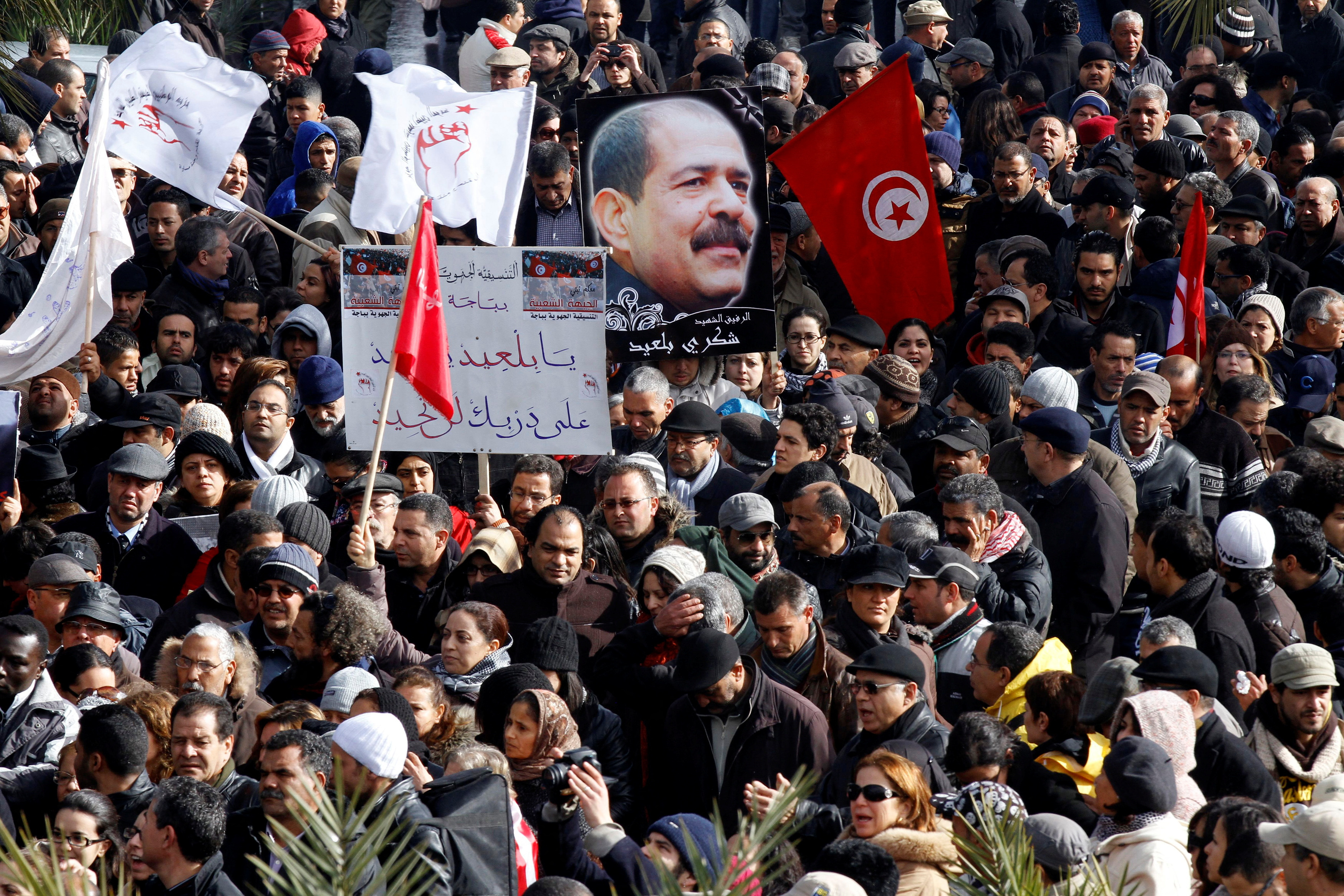 Tunisians hold a placard with an image of the late secular opposition leader Chokri Belaid during his funeral procession in the Jebel Jelloud district in Tunis