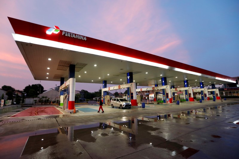 Worker walks past a car at a state-owned Pertamina petrol station in Bekasi, on the outskirts of Jakarta
