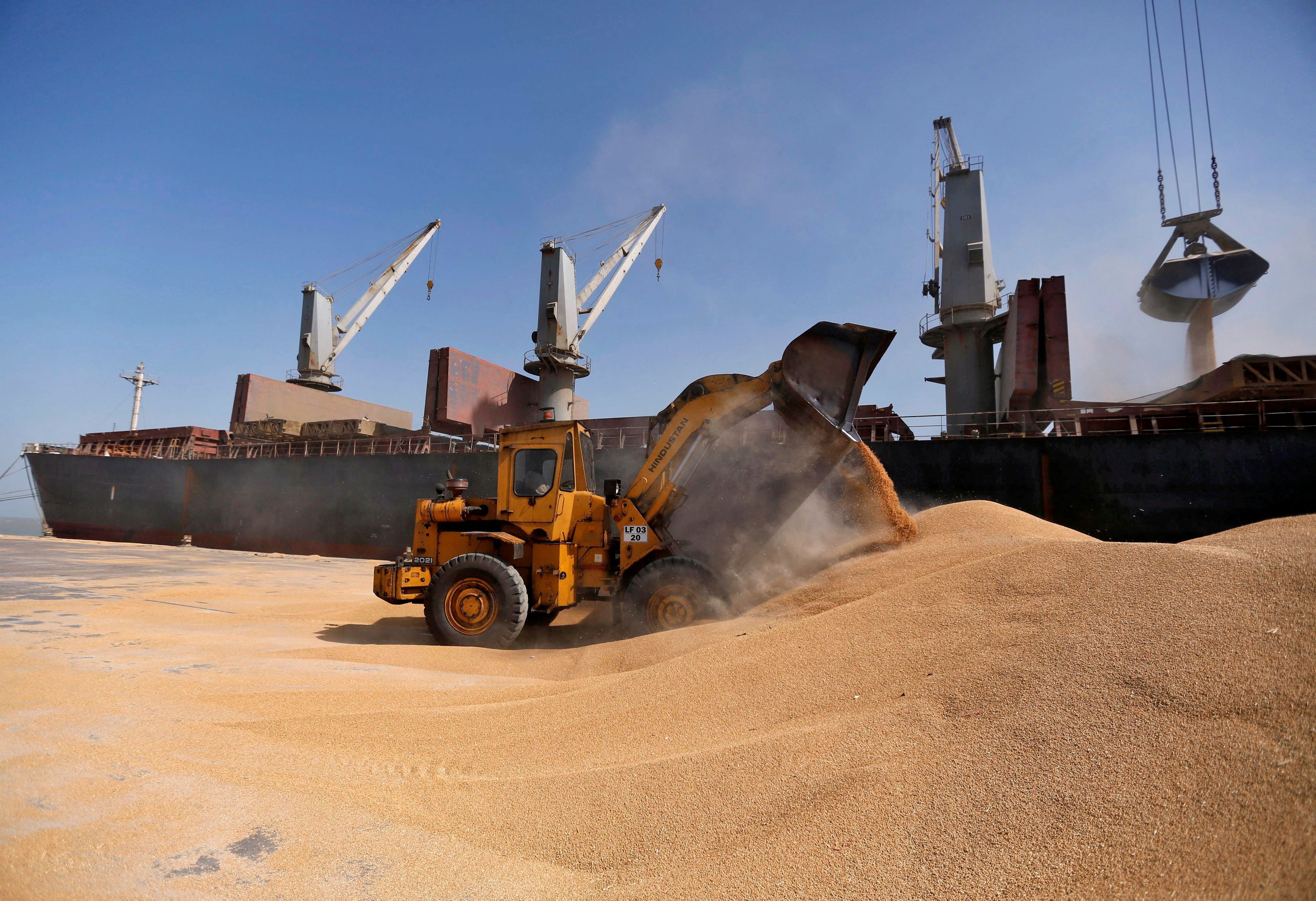A dozer unloads wheat next to a ship at Mundra Port, in Gujarat