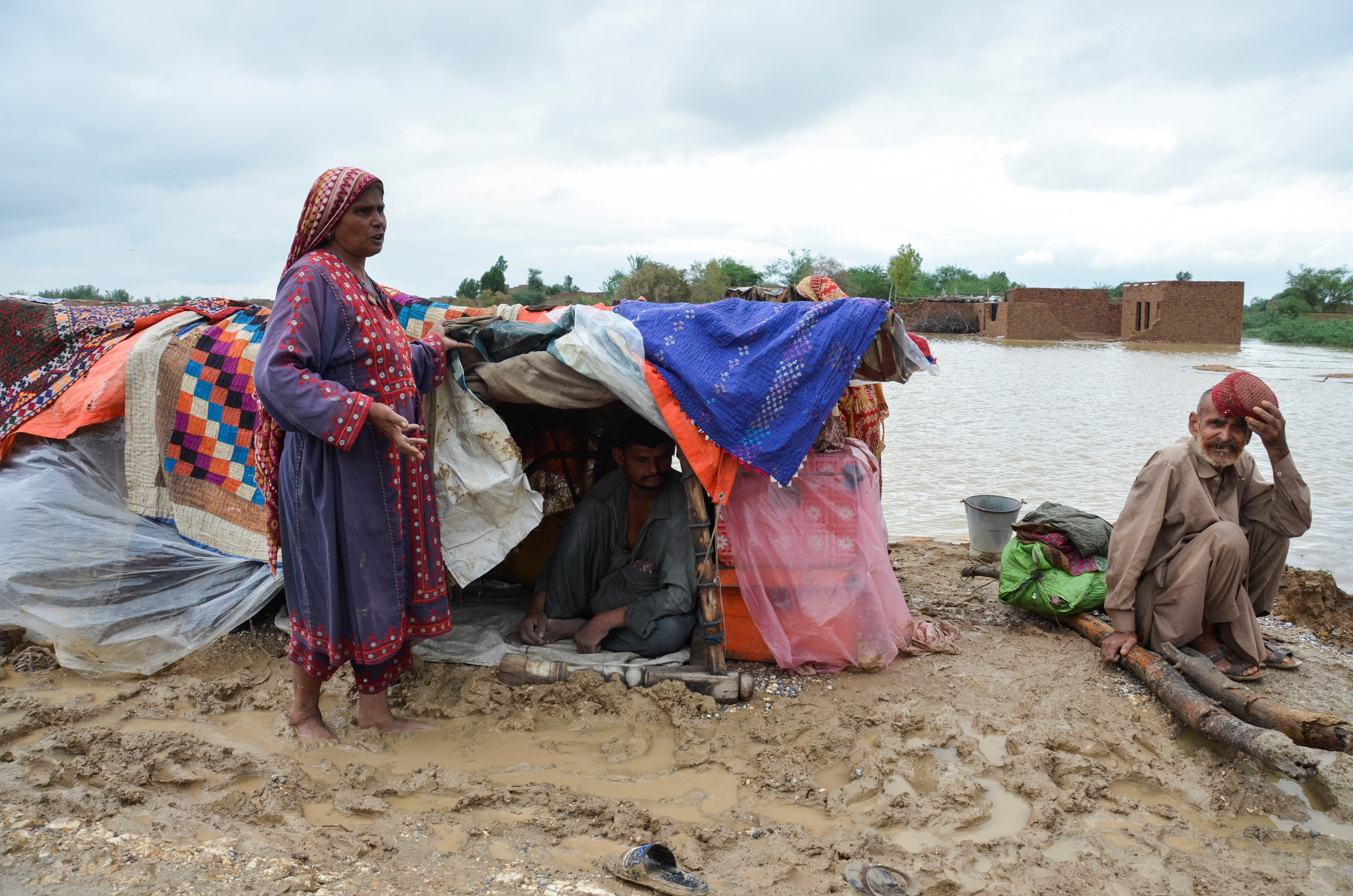 A family takes refuge on a higher ground following rains and floods during the monsoon season in Dera Allah Yar