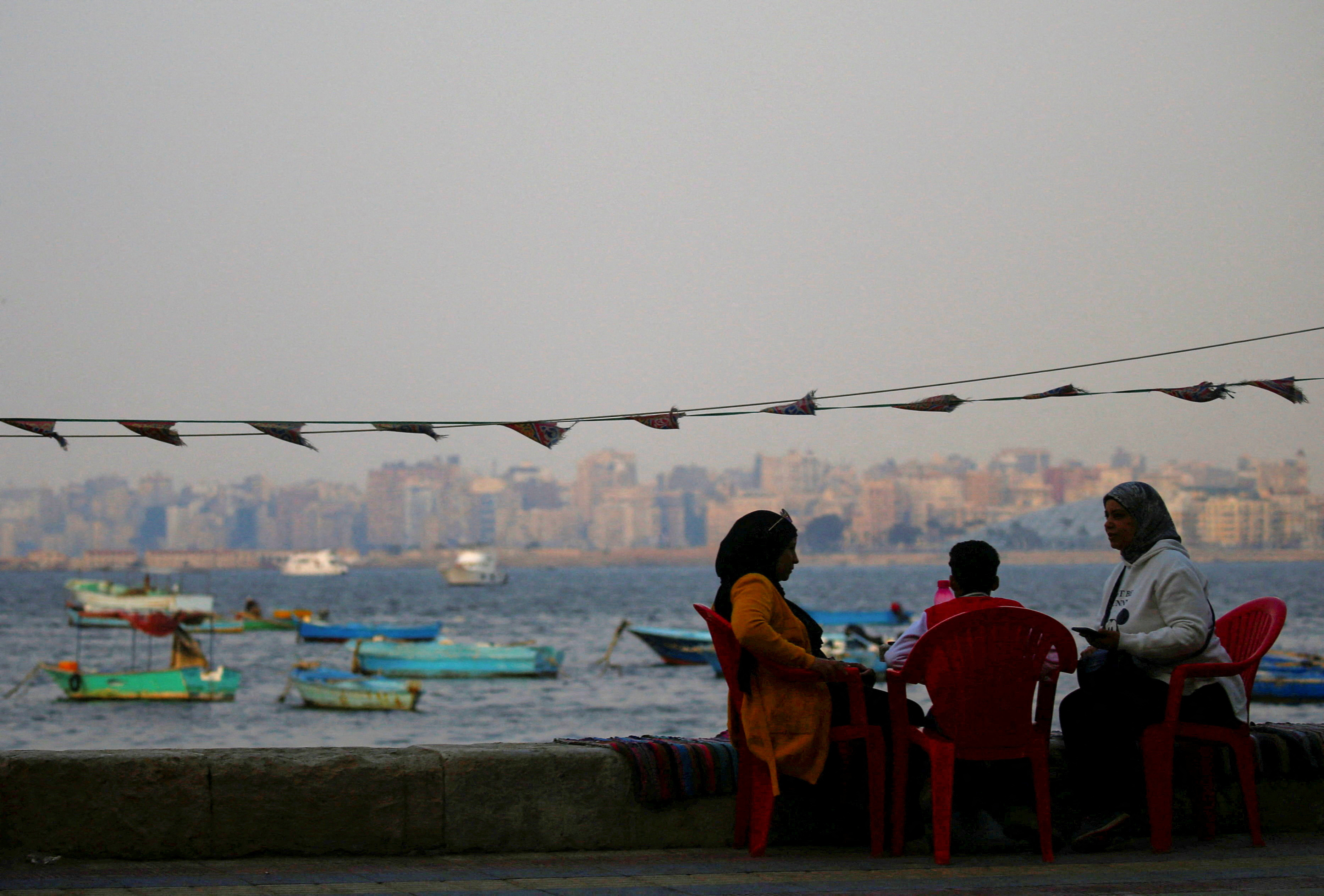 A family sits at a cafe on the shore of the Mediterranean port city of Alexandria