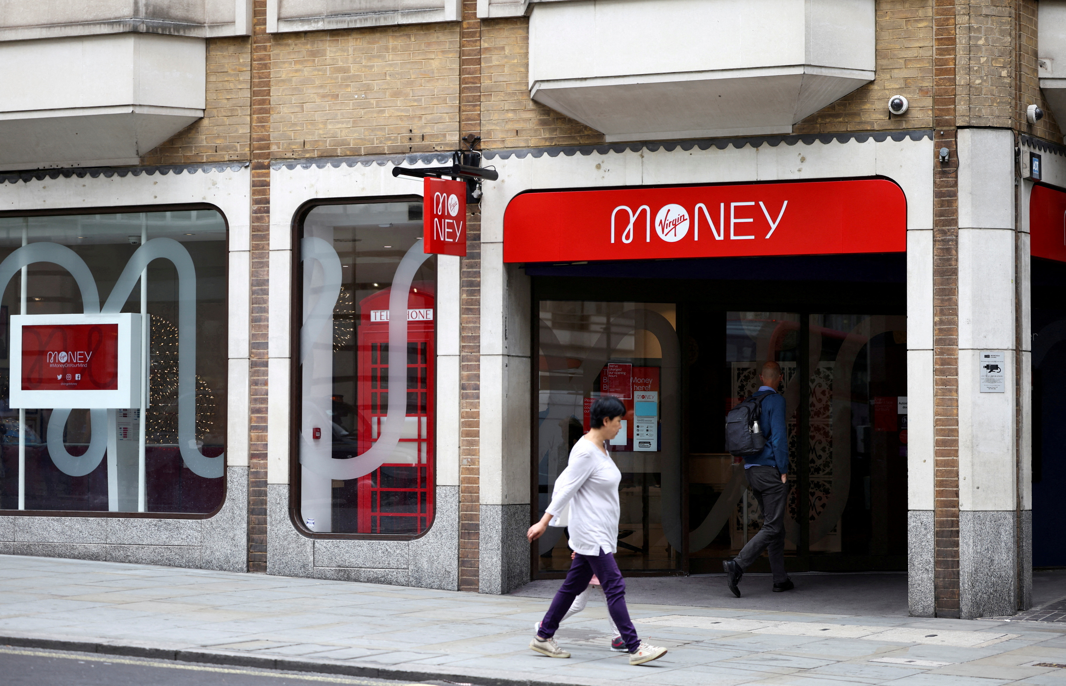 FILE PHOTO: People walk past a Virgin Money store in central London