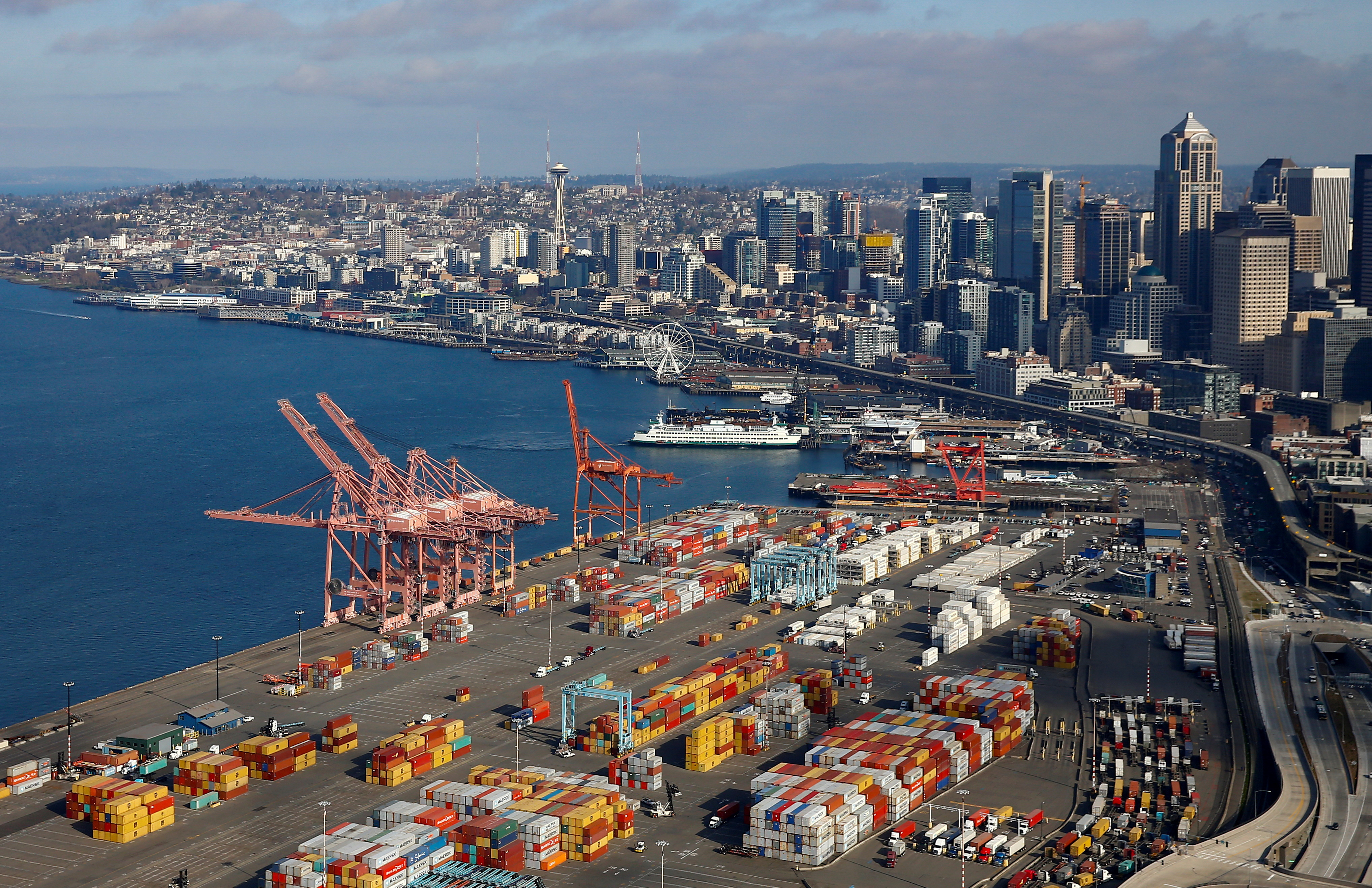 An aerial photo looking north shows shipping containers at the Port of Seattle and the Elliott Bay waterfront in Seattle