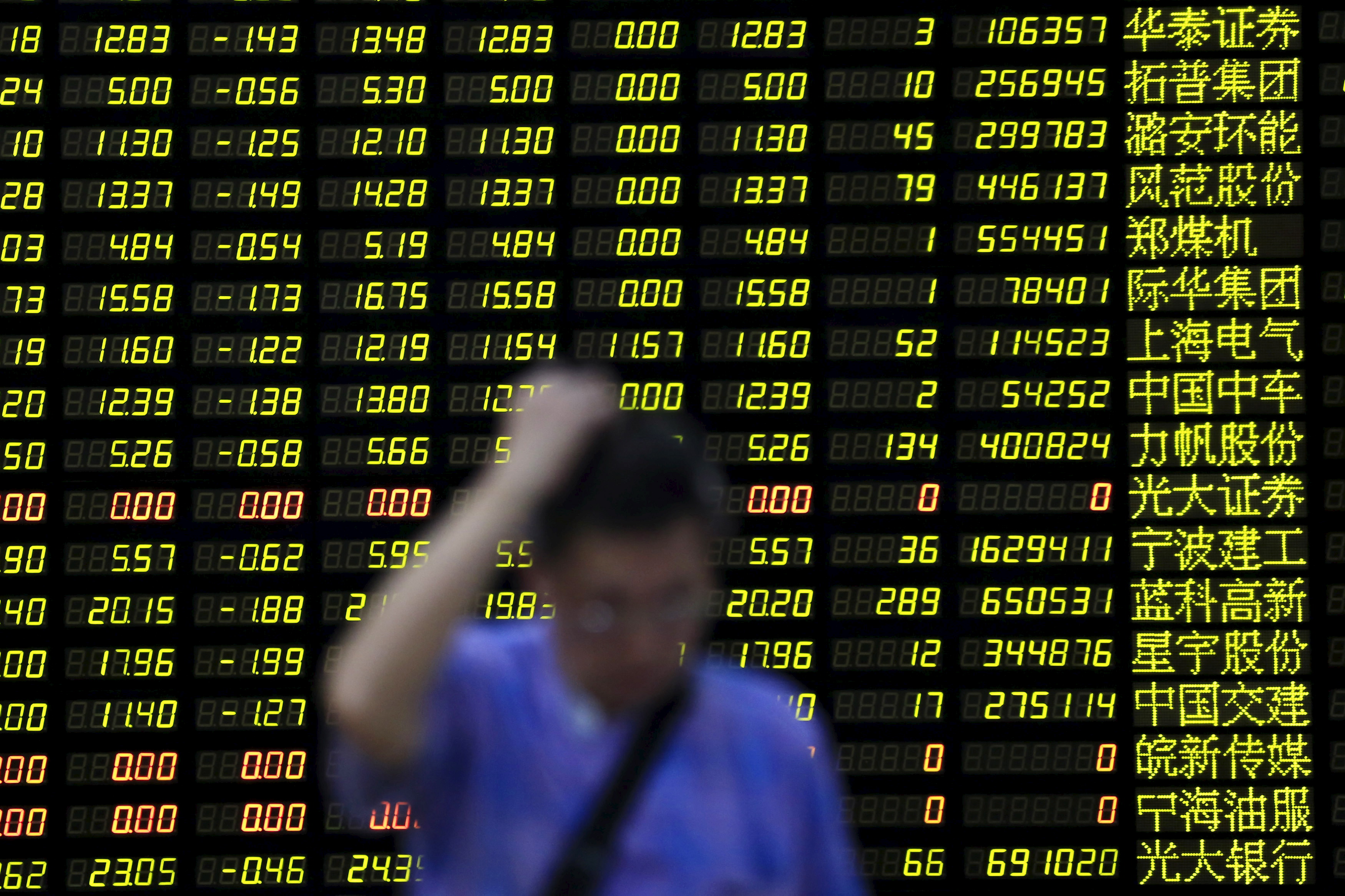 FILE PHOTO - An investor stands in front of electronic board showing stock information at brokerage house in Shanghai