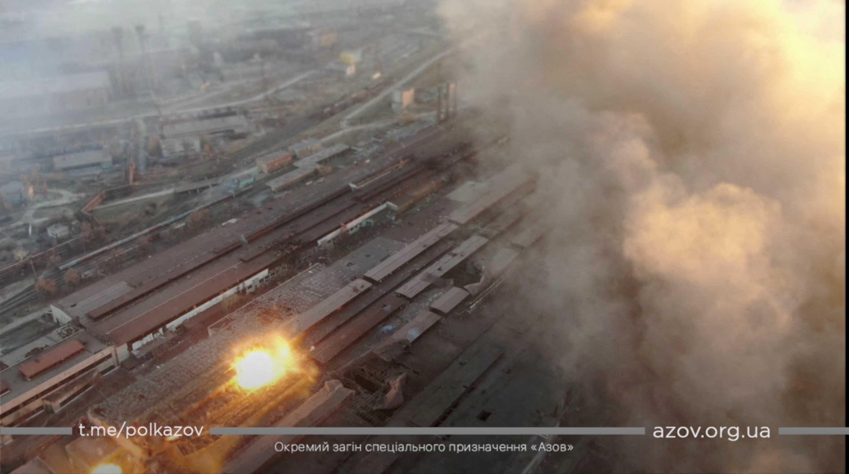Multiple explosions and rising smoke are seen around an industrial compound, in Mariupol