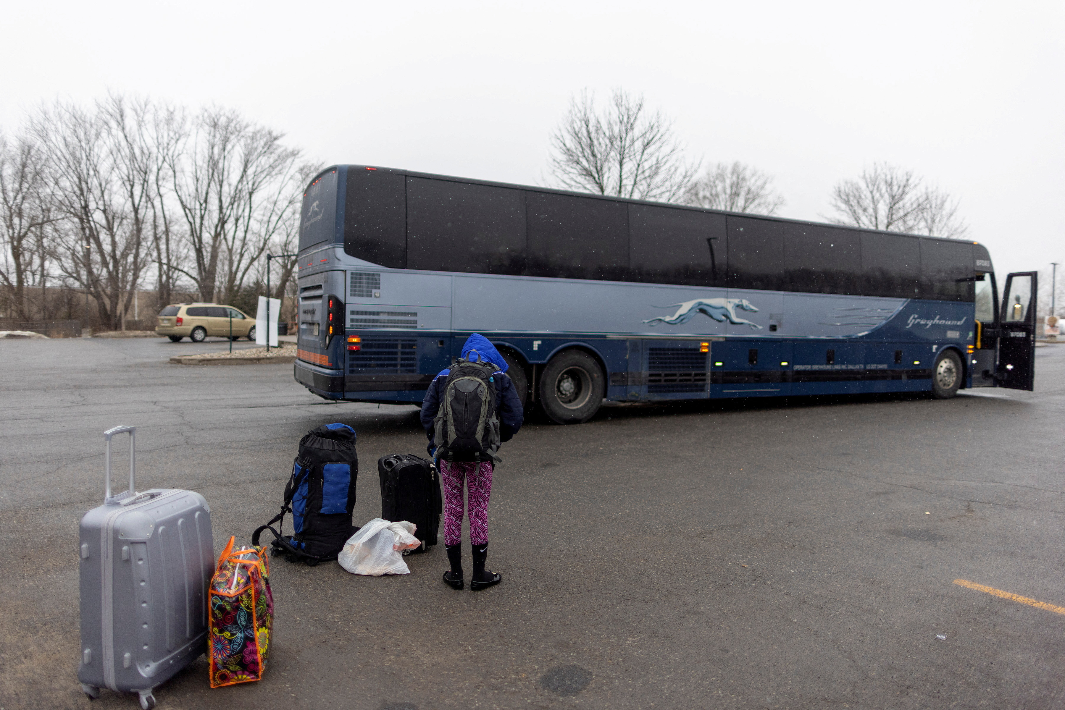 People wait for transport to cross into Canada at Roxham Road, in Plattsburgh