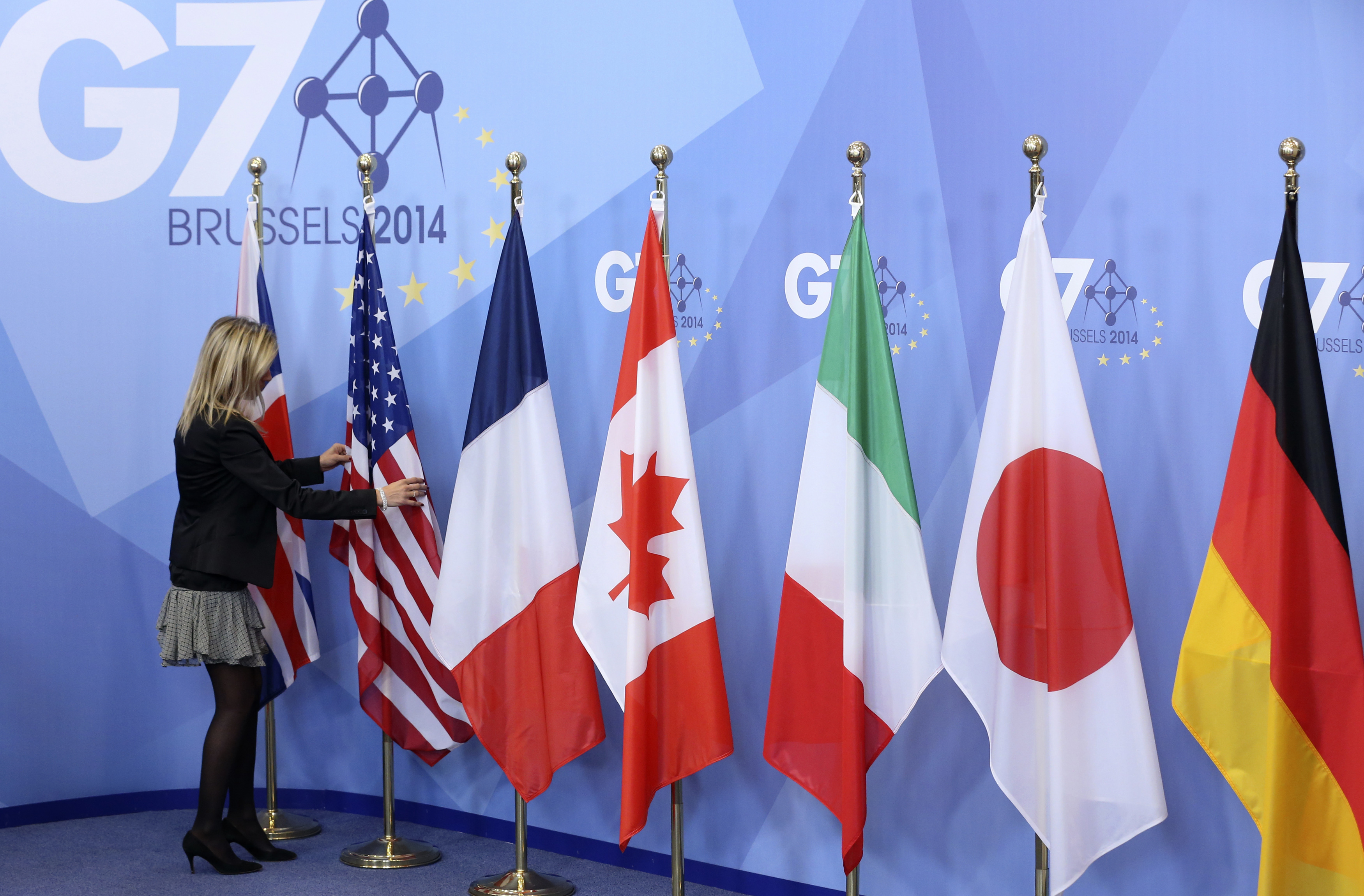 An official adjusts flags during the G7 summit at the European Council building in Brussels