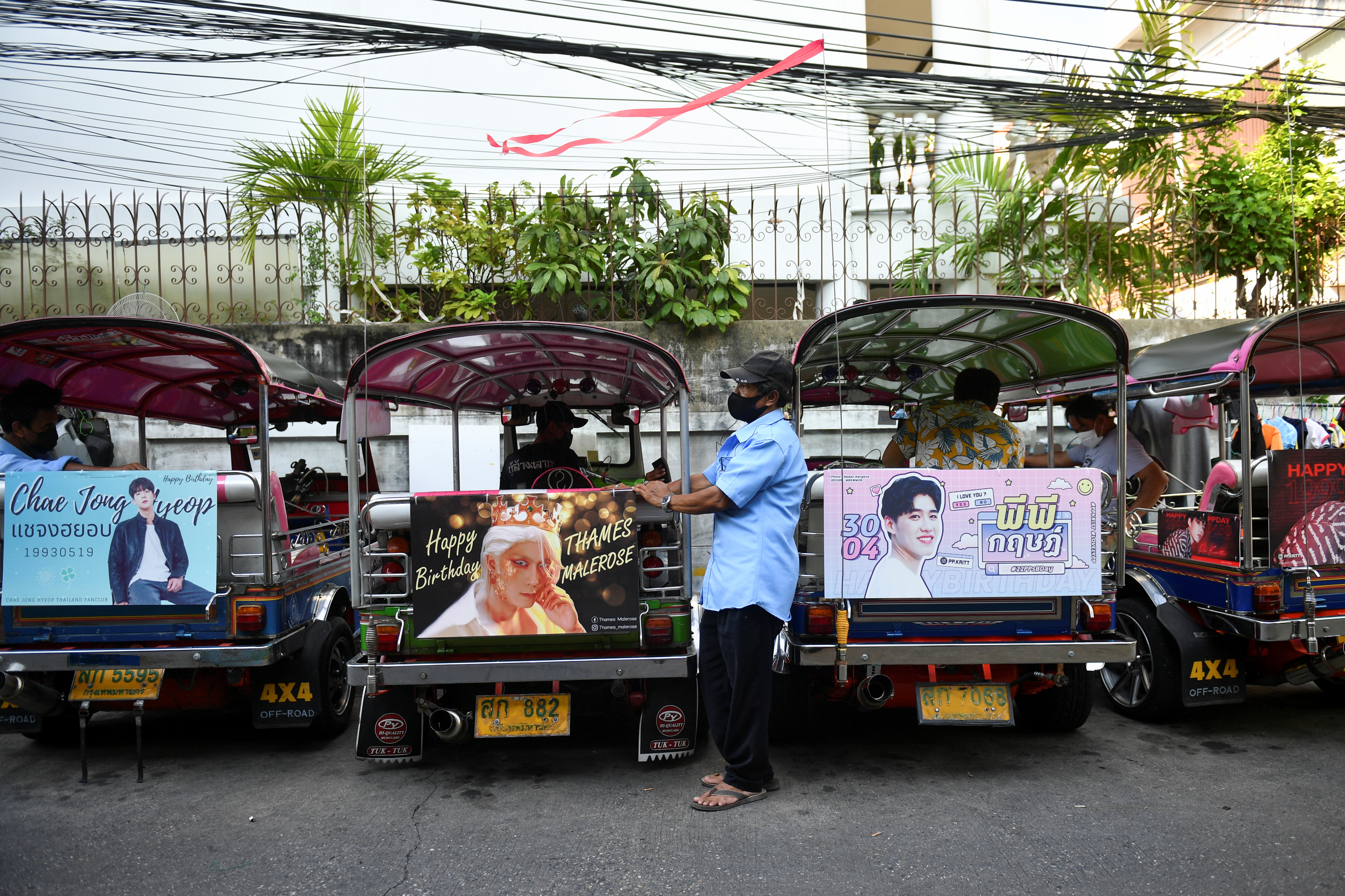 Tuk-tuk drivers, with their vehicles decorated with banners of Thai and Korean stars, wait for customers in Bangkok