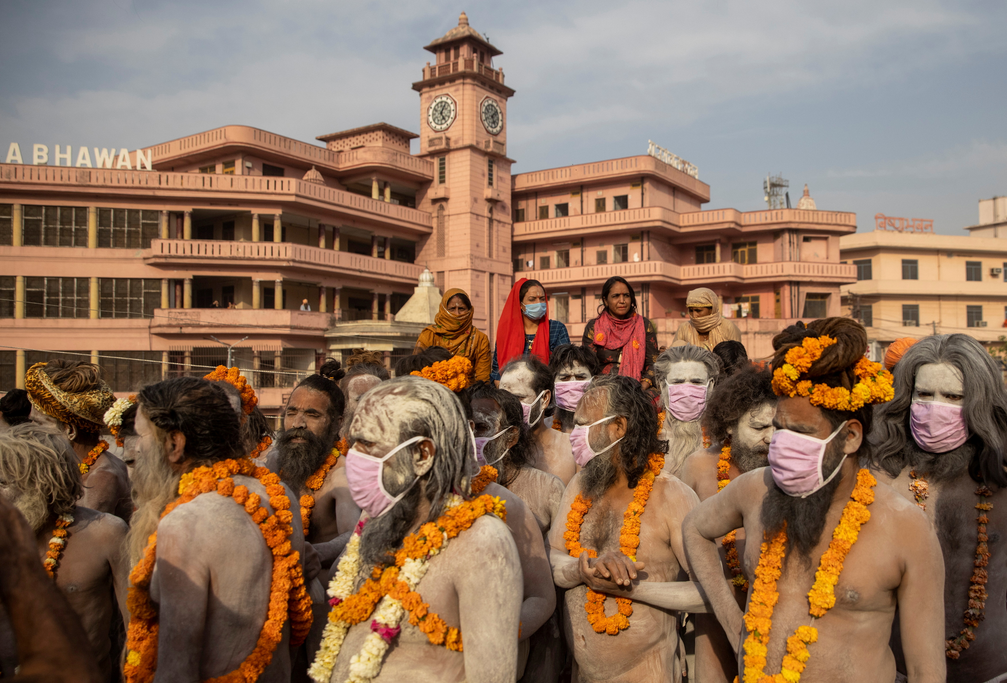 Naga Sadhus, or Hindu holy men wearing face masks wait before the procession for taking a dip in the Ganges river during Shahi Snan at 