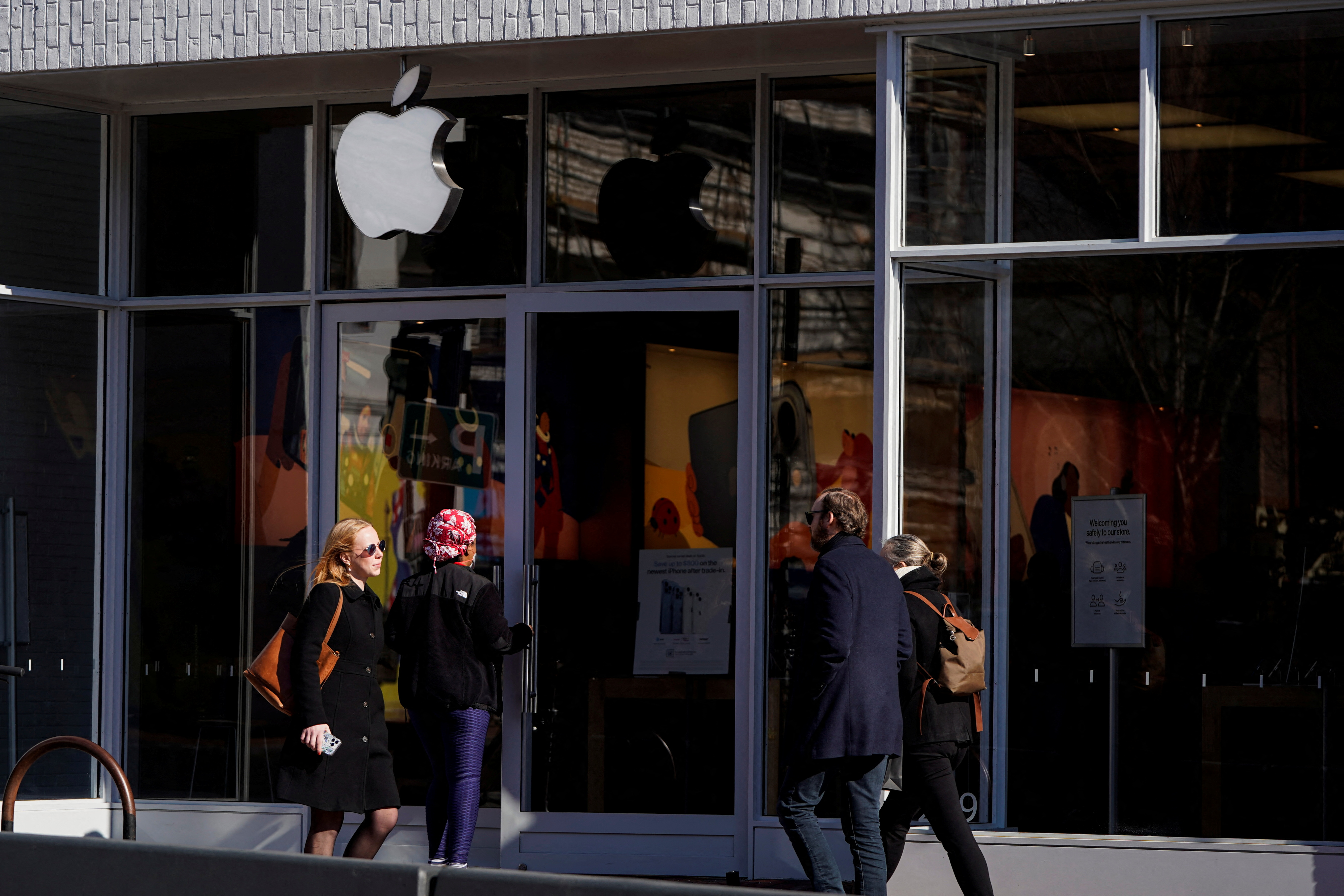 Pedestrians walk past an Apple store as Apple Inc. reports its fourth quarter results in Washington, U.S., January 27, 2022. REUTERS/Joshua Roberts