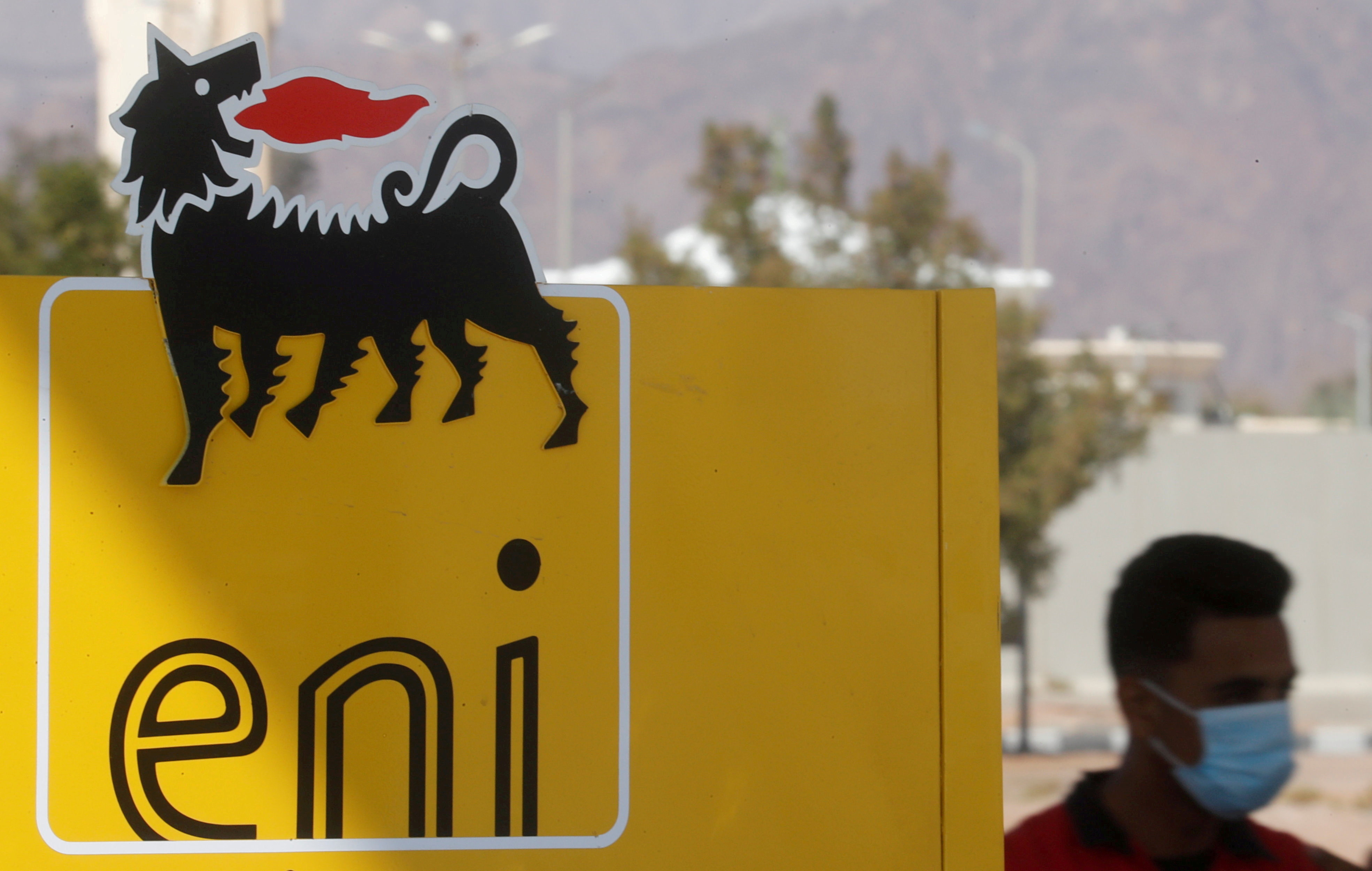 A man wearing a face mask walks near the sign of Italian energy Eni company at a gas station in the Red Sea resort of Sharm el-Sheikh