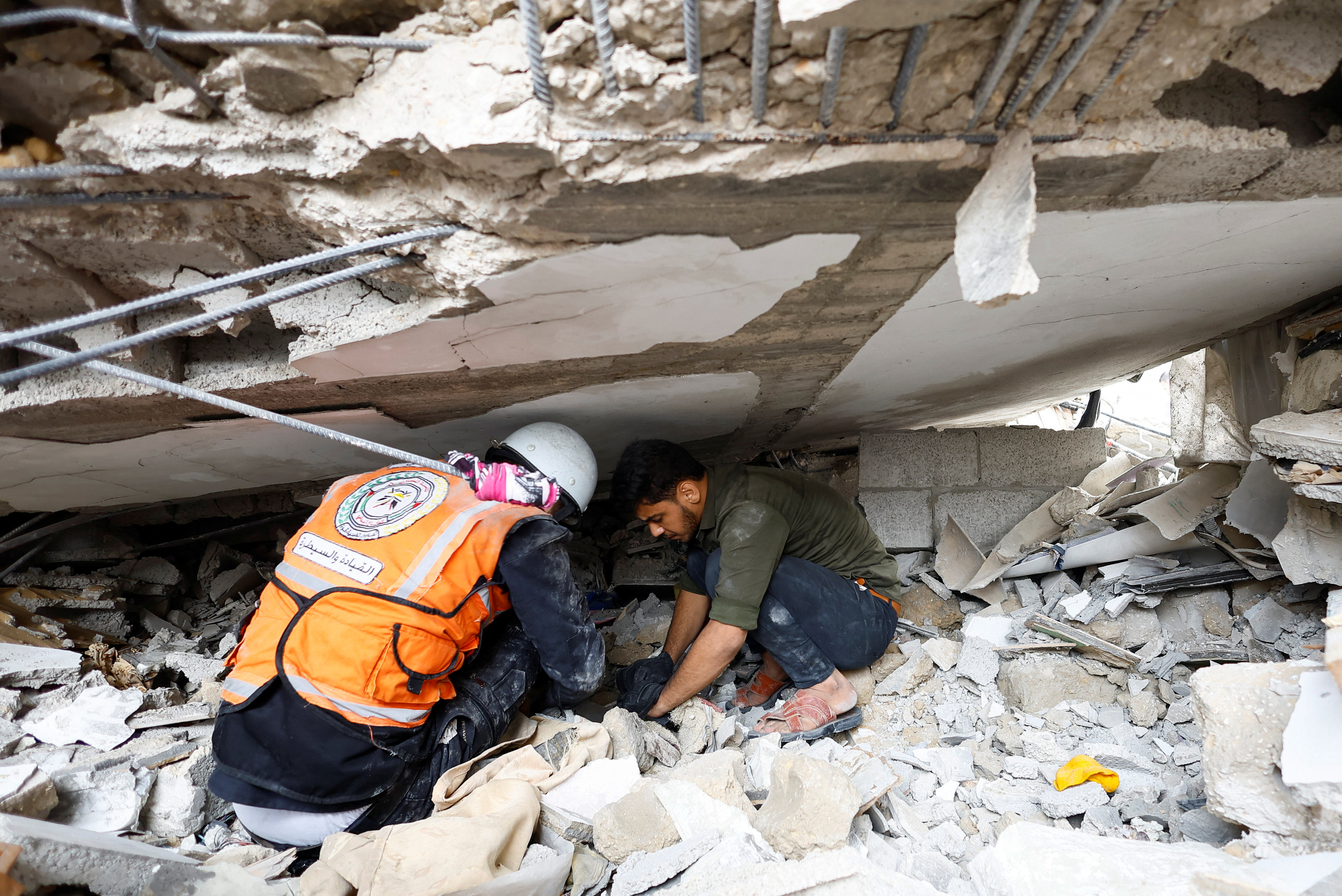Emergency personnel and people check the damage at the site of Israeli strikes on houses in Khan Younis