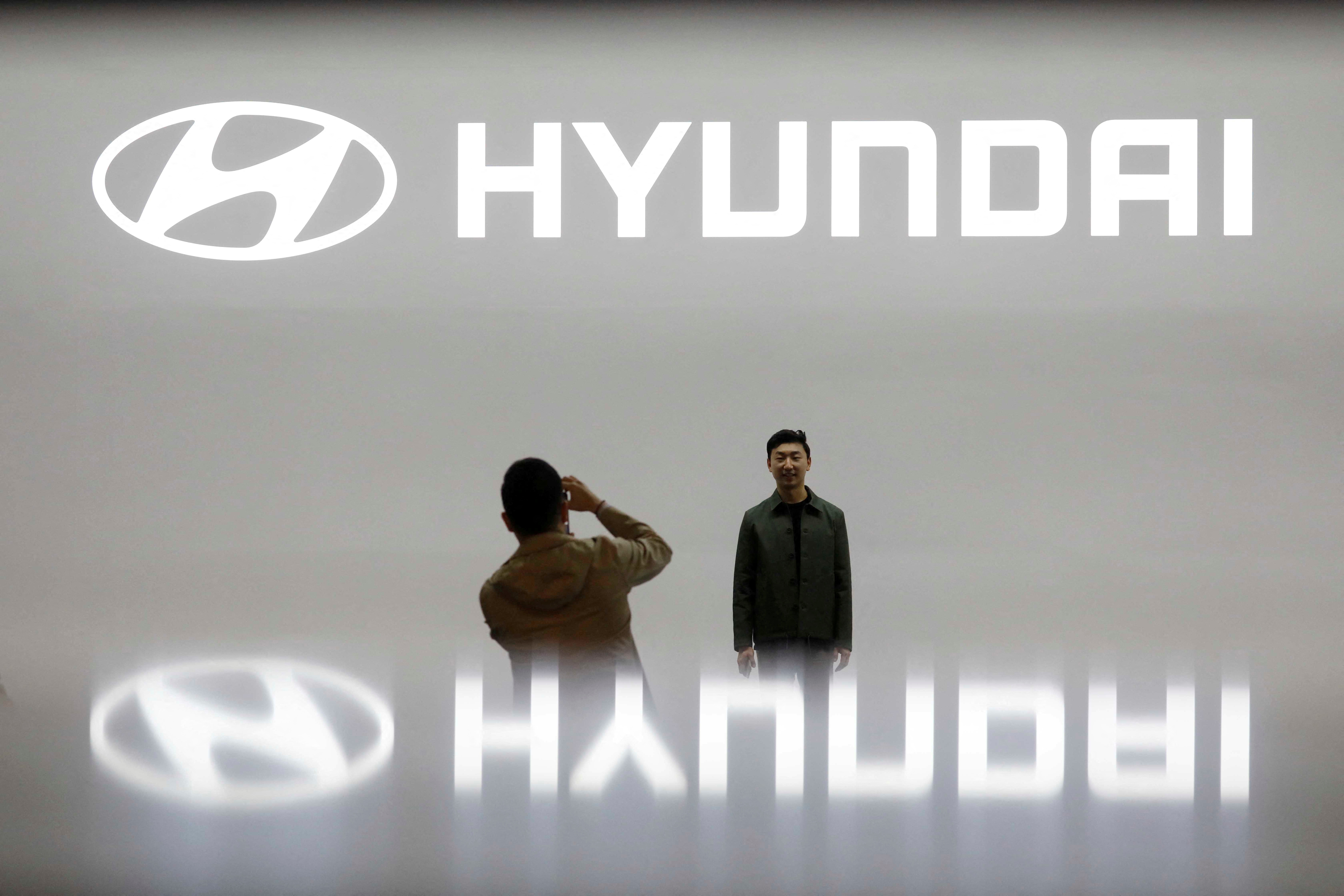 Visitors take photographs in front of the logo of Hyundai Motor during the 2019 Seoul Motor Show in Goyang